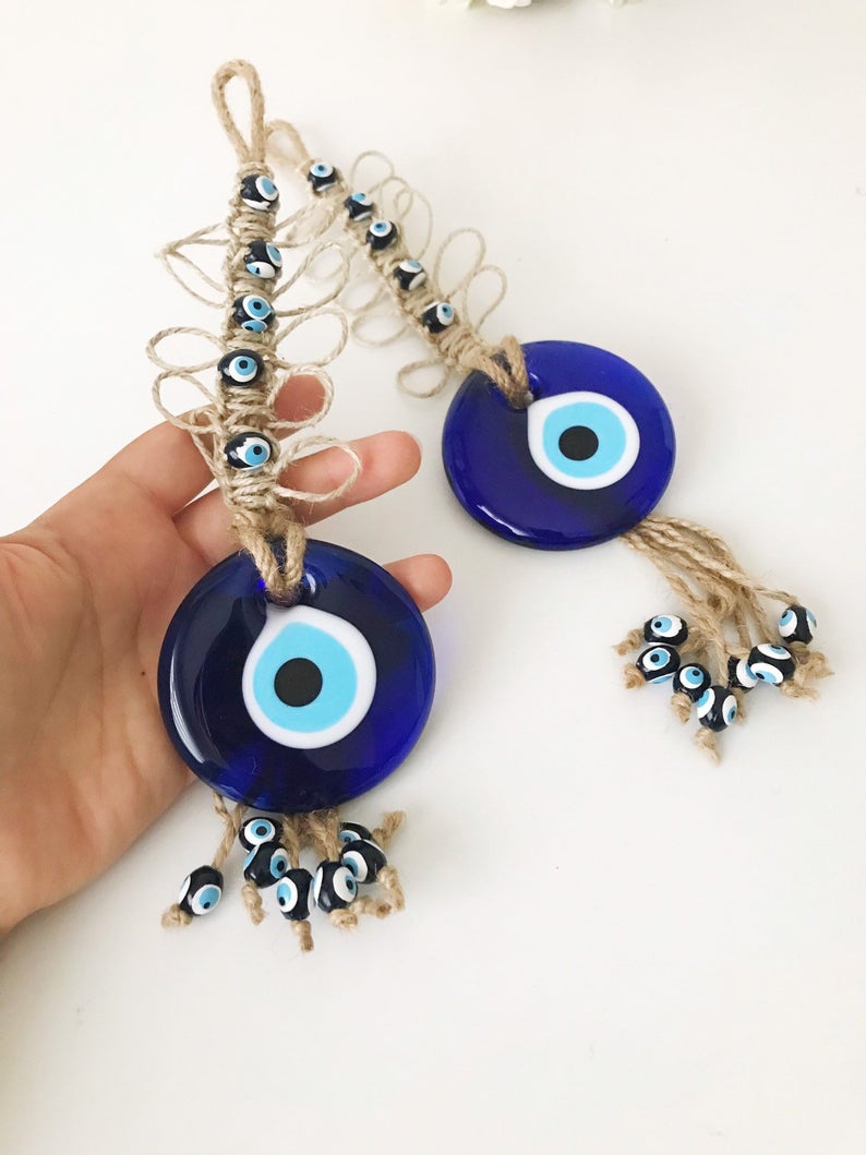 Handmade blue evil eye macrame wall hanging featuring a large evil eye bead and tiny blue beads, perfect for home decor.