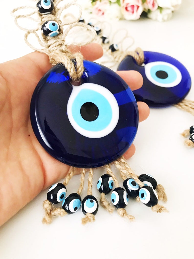 Handmade blue evil eye macrame wall hanging featuring a large evil eye bead and tiny blue beads, perfect for home decor.