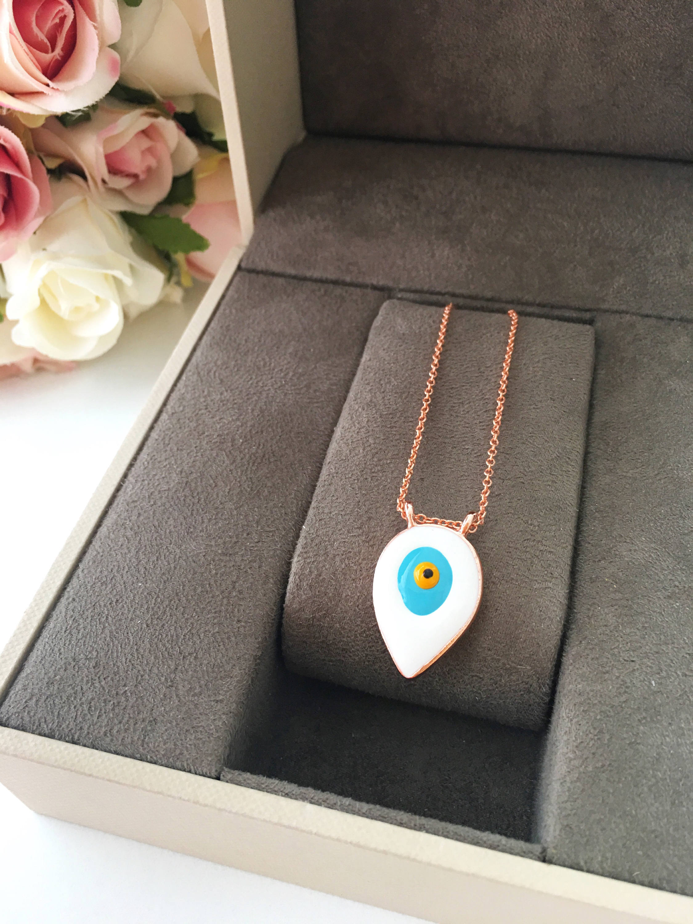 A beautiful Blue Evil Eye Necklace featuring white and blue enamel charms on a rose gold stainless steel chain, symbolizing protection and good luck.