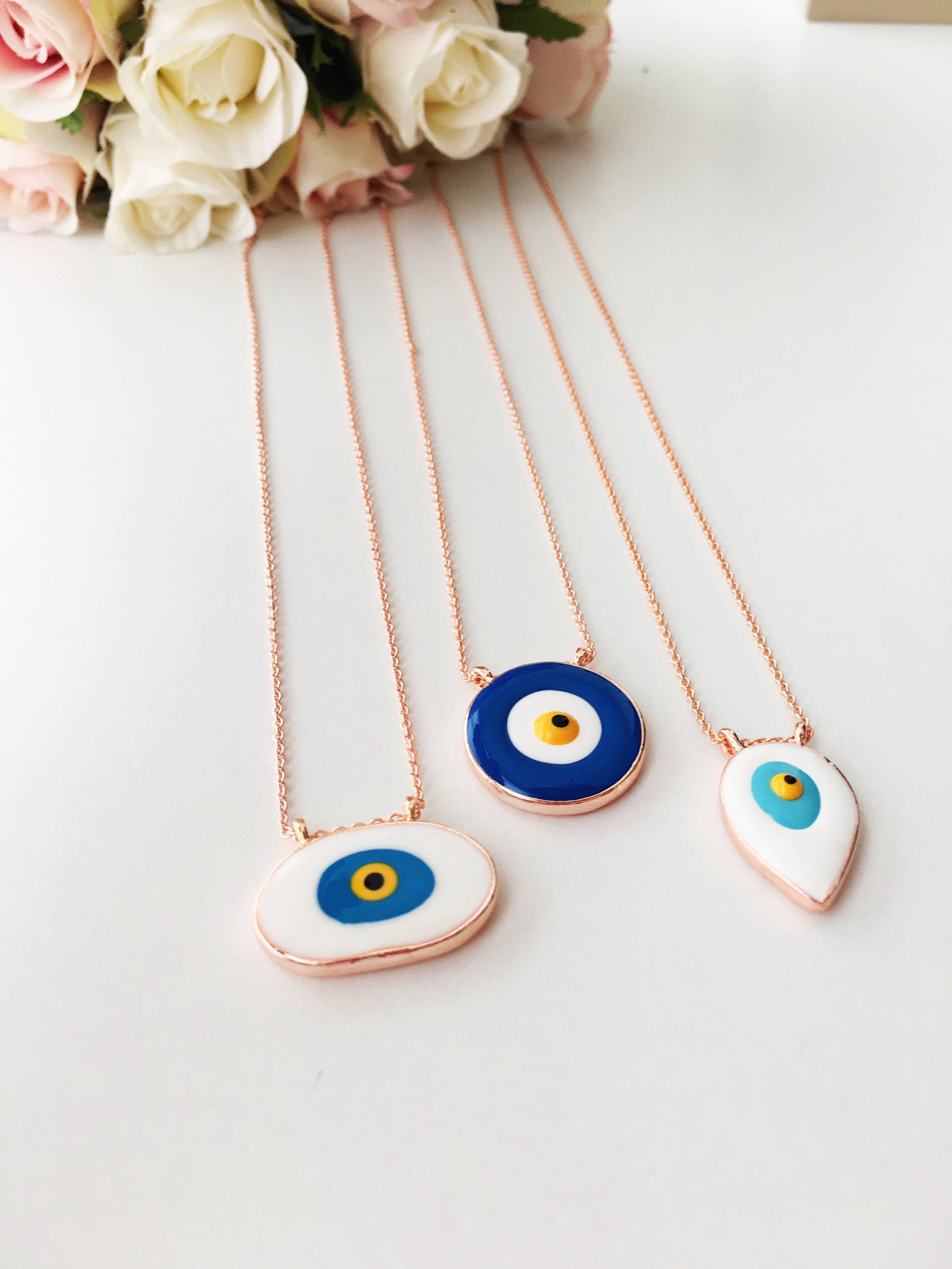 A beautiful Blue Evil Eye Necklace featuring white and blue enamel charms on a rose gold stainless steel chain, symbolizing protection and good luck.