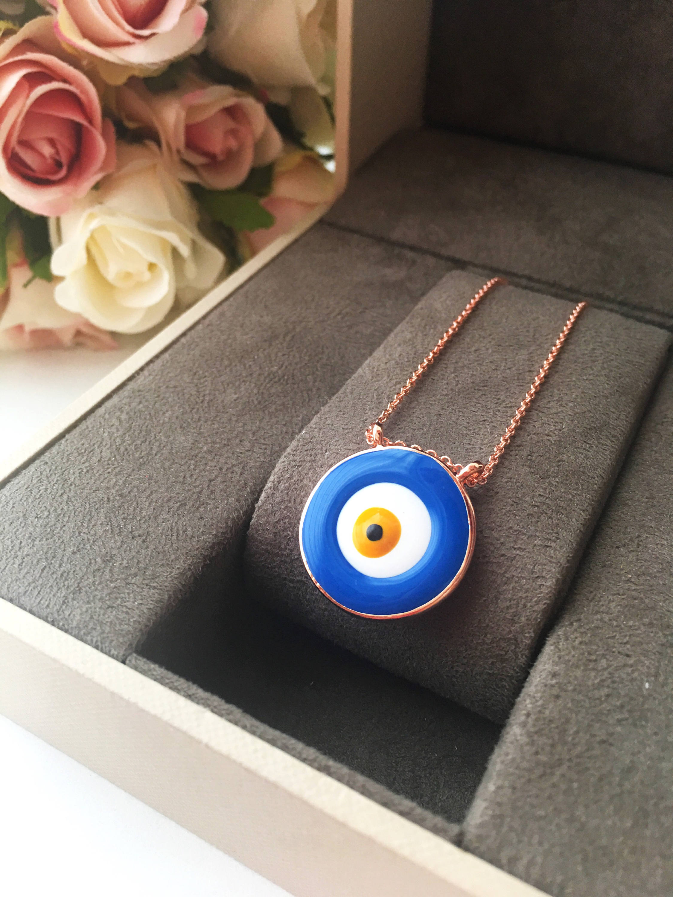 A beautiful Blue Evil Eye Necklace featuring white and blue enamel charms on a rose gold stainless steel chain, symbolizing protection and good luck.