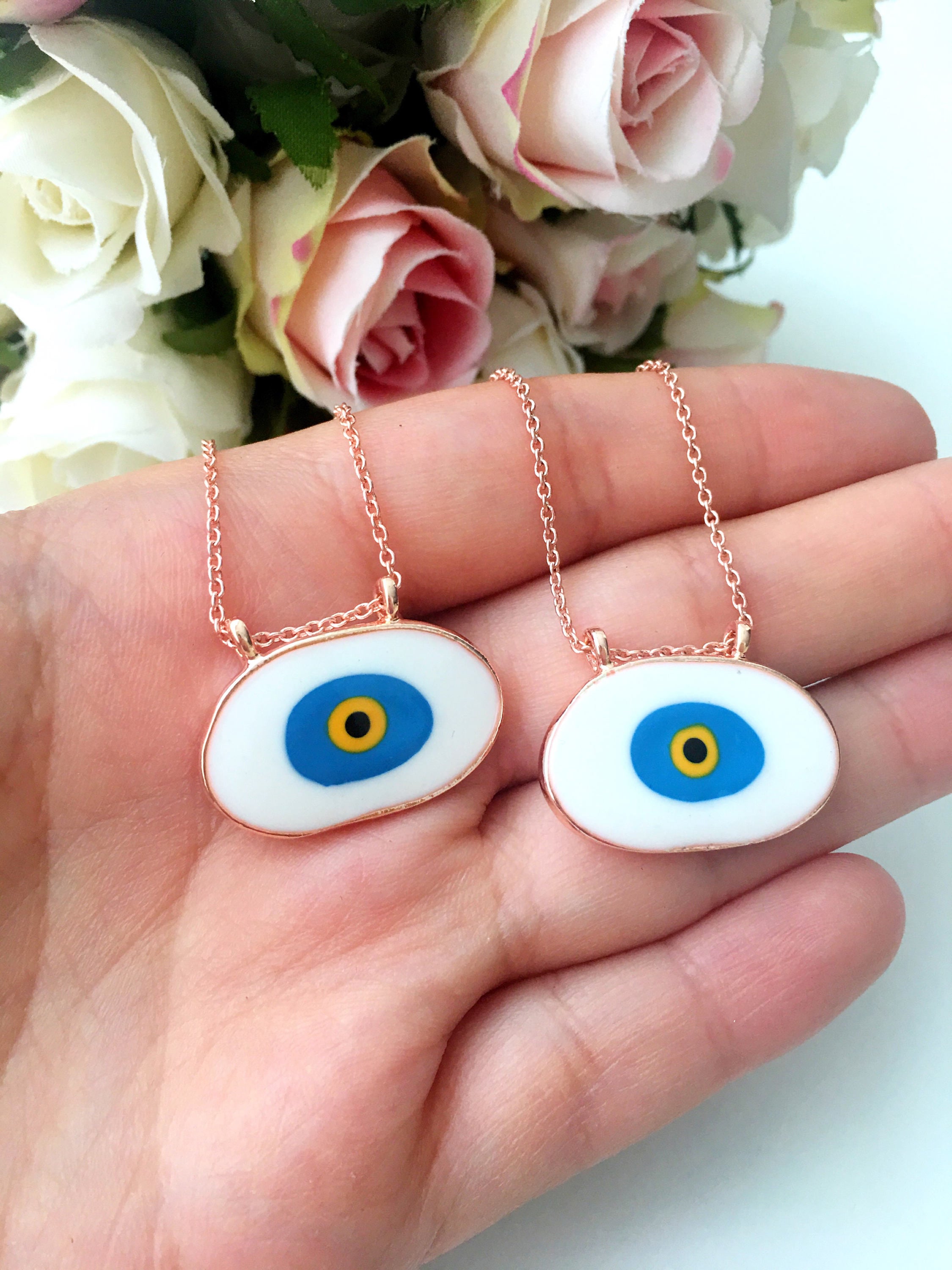 A beautiful Blue Evil Eye Necklace featuring white and blue enamel charms on a rose gold stainless steel chain, symbolizing protection and good luck.