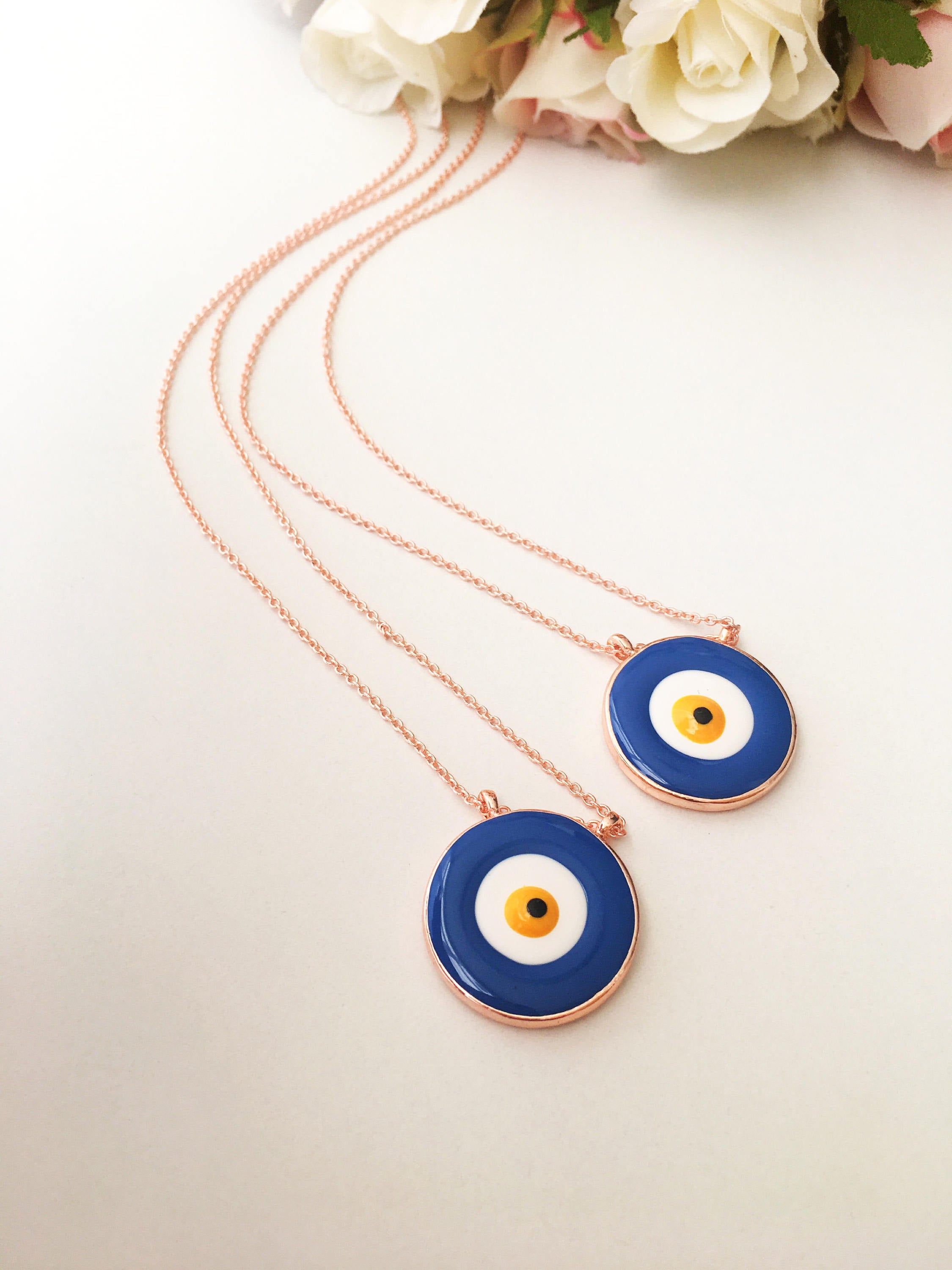 A beautiful Blue Evil Eye Necklace featuring white and blue enamel charms on a rose gold stainless steel chain, symbolizing protection and good luck.