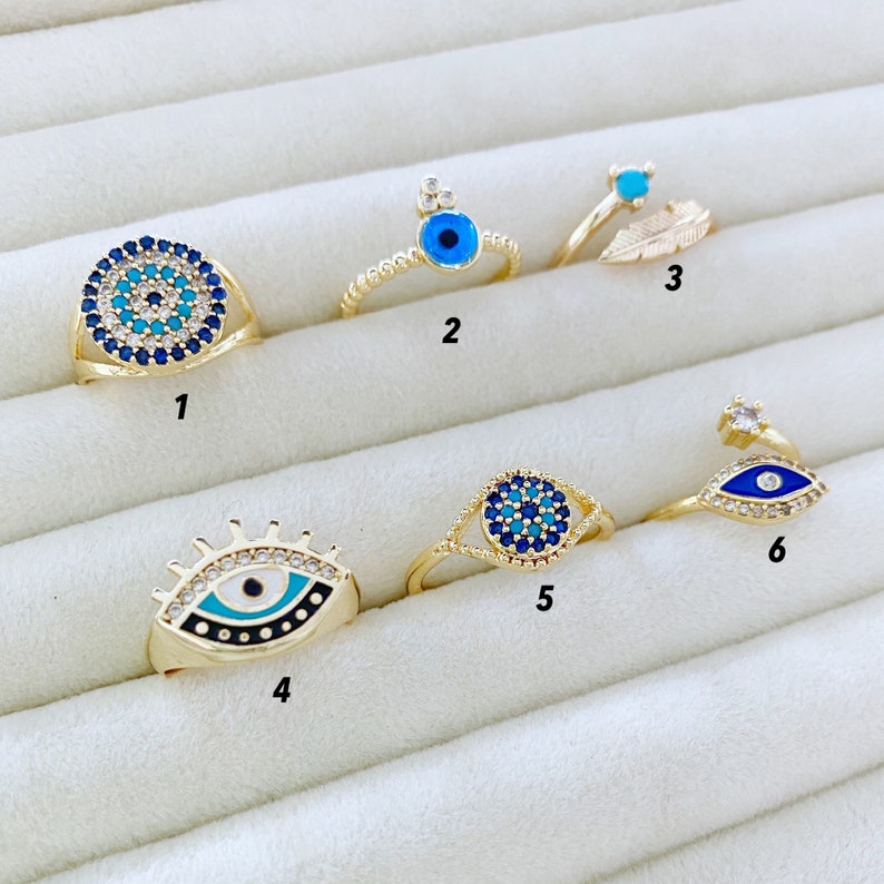 A beautiful set of adjustable blue evil eye rings with gold bands and zircon accents, showcasing six unique styles.