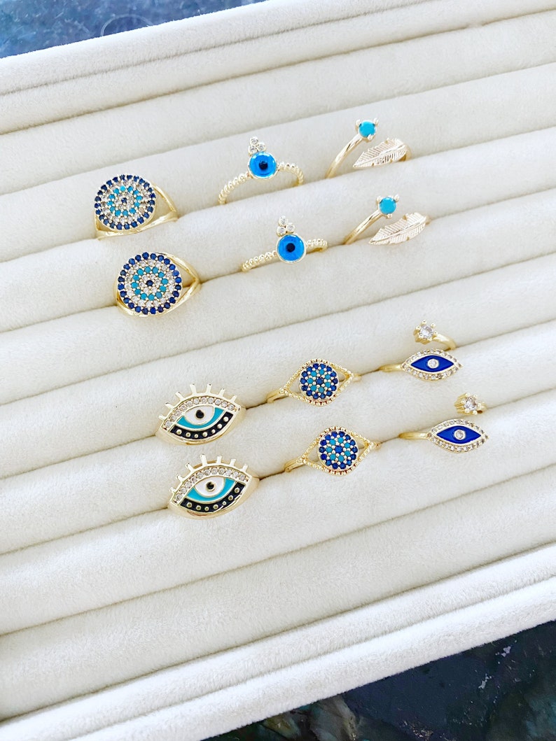 A beautiful set of adjustable blue evil eye rings with gold bands and zircon accents, showcasing six unique styles.