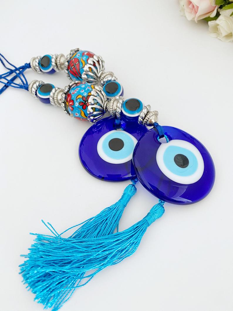 A beautiful handmade Blue Evil Eye Wall Hanging featuring a central evil eye bead and decorative tassel, perfect for home decor.