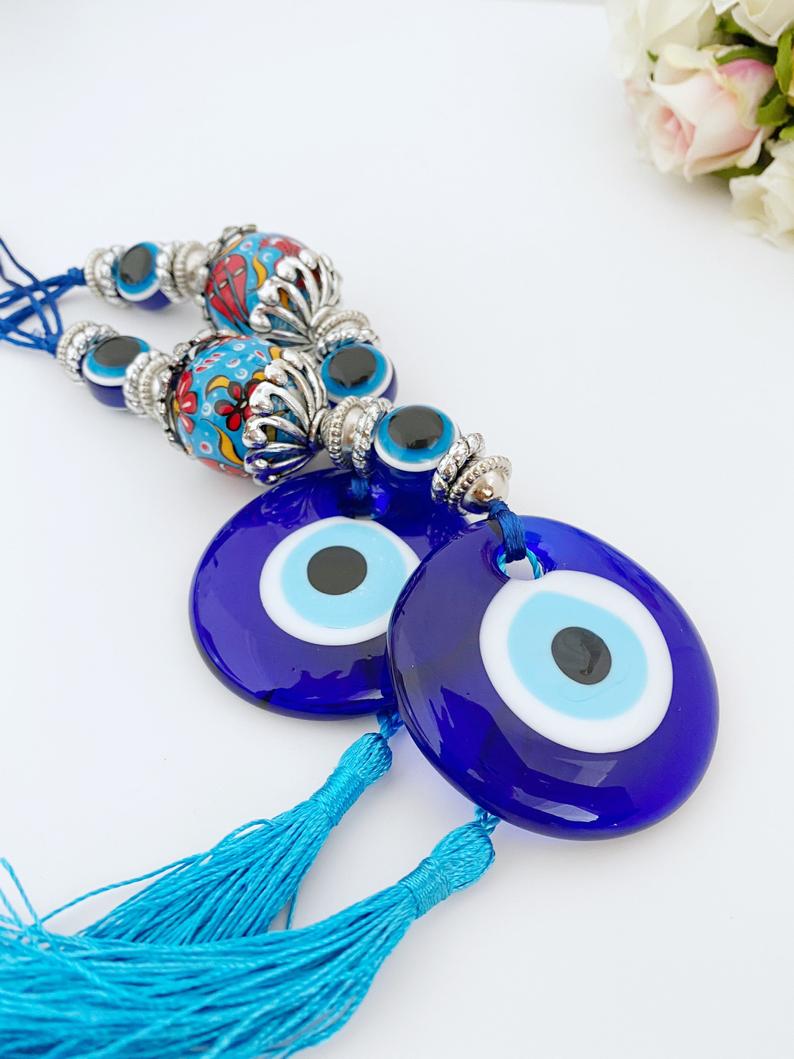 A beautiful handmade Blue Evil Eye Wall Hanging featuring a central evil eye bead and decorative tassel, perfect for home decor.