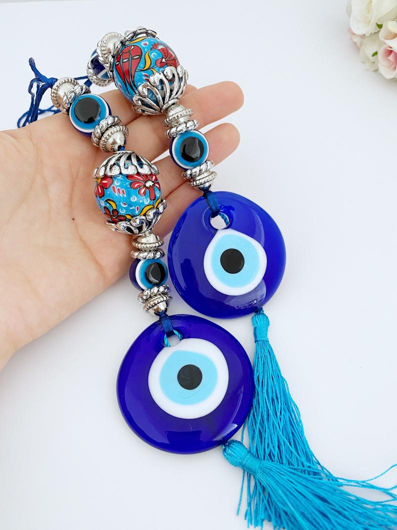 A beautiful handmade Blue Evil Eye Wall Hanging featuring a central evil eye bead and decorative tassel, perfect for home decor.