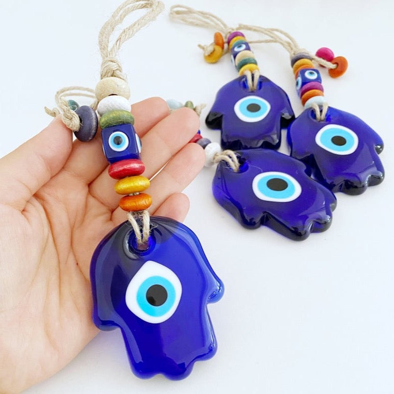 A beautiful Blue Evil Eye Wall Hanging featuring a handmade glass Hamsa design, showcasing intricate macrame details and vibrant colors.