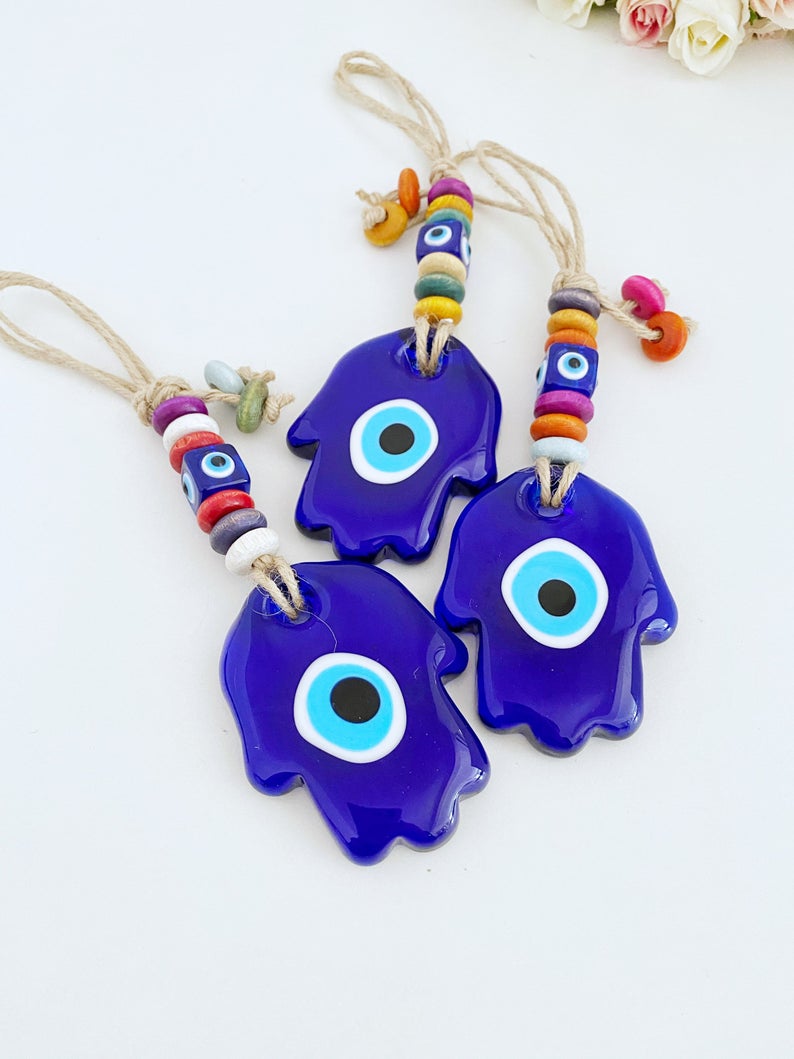 A beautiful Blue Evil Eye Wall Hanging featuring a handmade glass Hamsa design, showcasing intricate macrame details and vibrant colors.