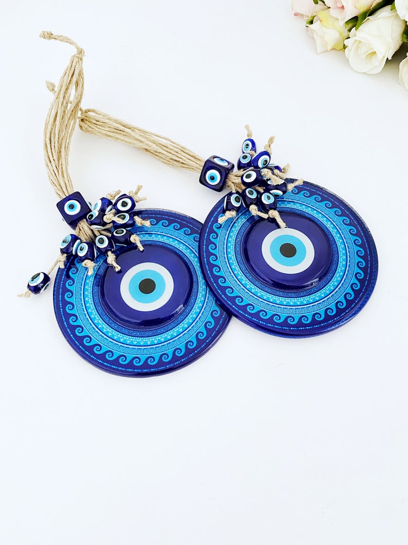 A beautifully handcrafted Blue Evil Eye Wall Hanging featuring a macrame design and a fused glass evil eye bead, perfect for home decor.