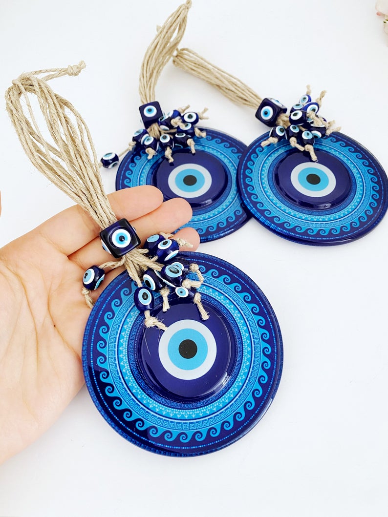 A beautifully handcrafted Blue Evil Eye Wall Hanging featuring a macrame design and a fused glass evil eye bead, perfect for home decor.