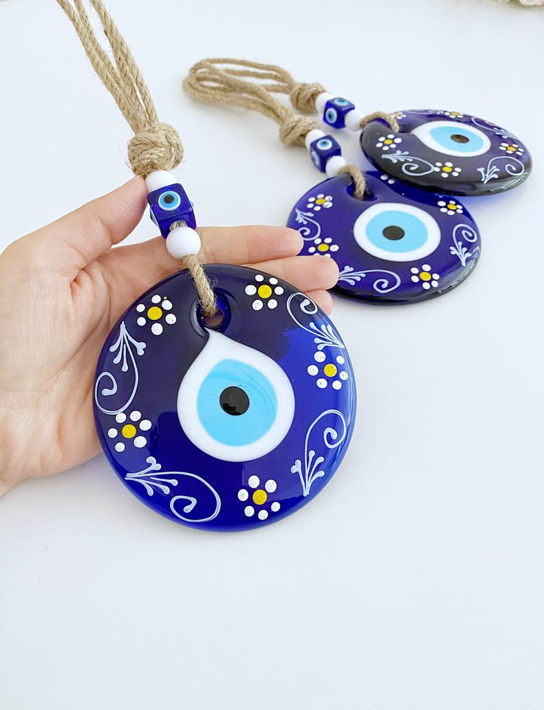 A beautifully crafted Blue Evil Eye Wall Hanging featuring macrame, painted evil eye beads, and white beads, perfect for home decor.