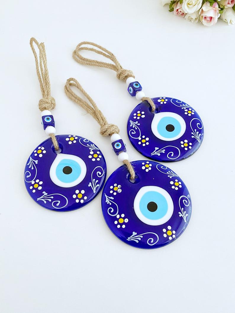 A beautifully crafted Blue Evil Eye Wall Hanging featuring macrame, painted evil eye beads, and white beads, perfect for home decor.