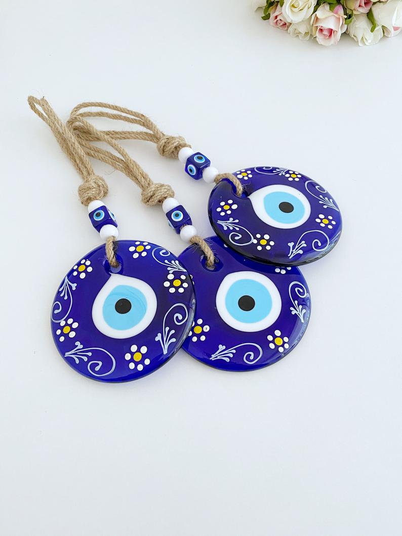 A beautifully crafted Blue Evil Eye Wall Hanging featuring macrame, painted evil eye beads, and white beads, perfect for home decor.