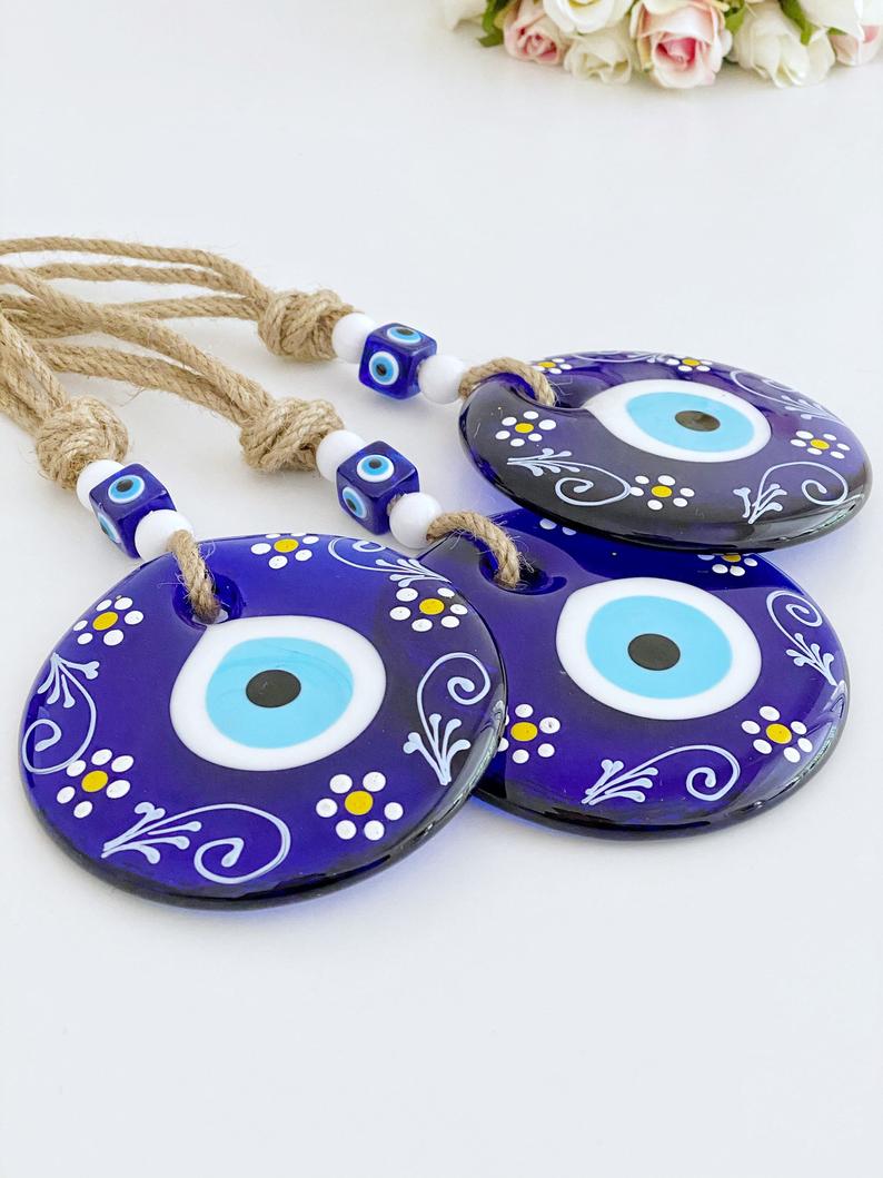 A beautifully crafted Blue Evil Eye Wall Hanging featuring macrame, painted evil eye beads, and white beads, perfect for home decor.