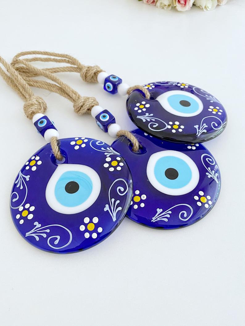 A beautifully crafted Blue Evil Eye Wall Hanging featuring macrame, painted evil eye beads, and white beads, perfect for home decor.