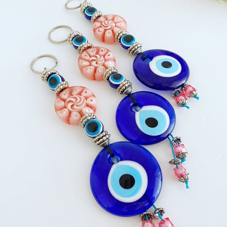 Handmade Blue Evil Eye Wall Hanging with pink beads, featuring a protective charm for home decoration.