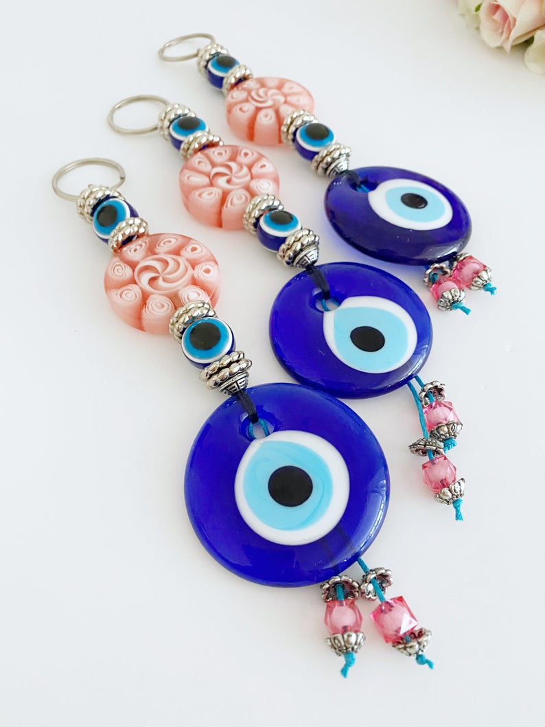 Handmade Blue Evil Eye Wall Hanging with pink beads, featuring a protective charm for home decoration.