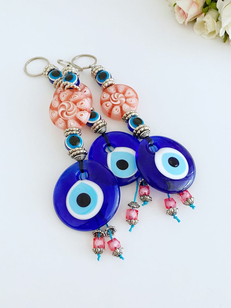 Handmade Blue Evil Eye Wall Hanging with pink beads, featuring a protective charm for home decoration.