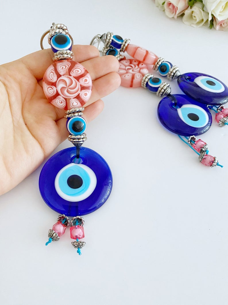 Handmade Blue Evil Eye Wall Hanging with pink beads, featuring a protective charm for home decoration.