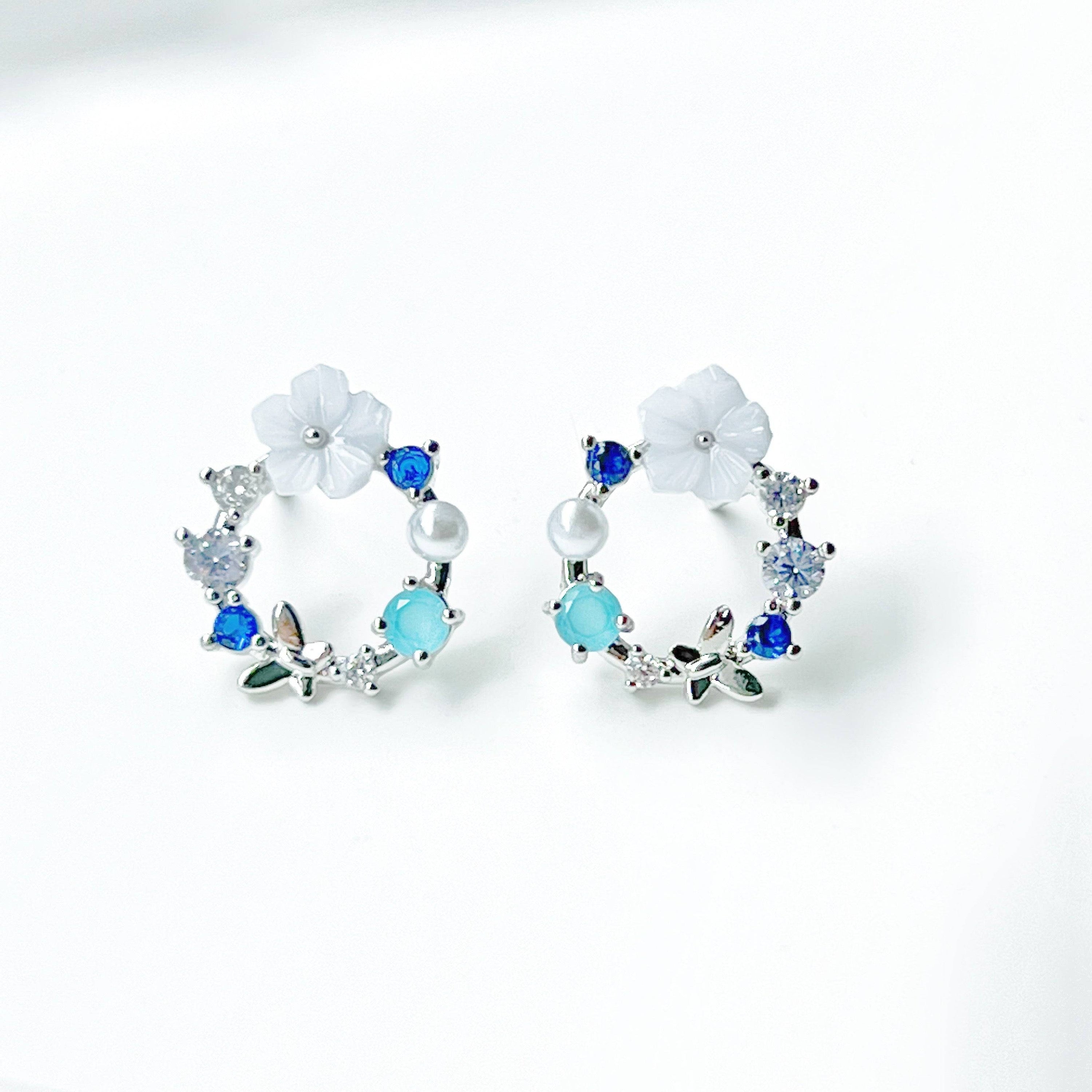 A pair of elegant blue flower wreath earrings featuring blue zircon and pearl, set in gold-plated bronze with sterling silver ear studs.