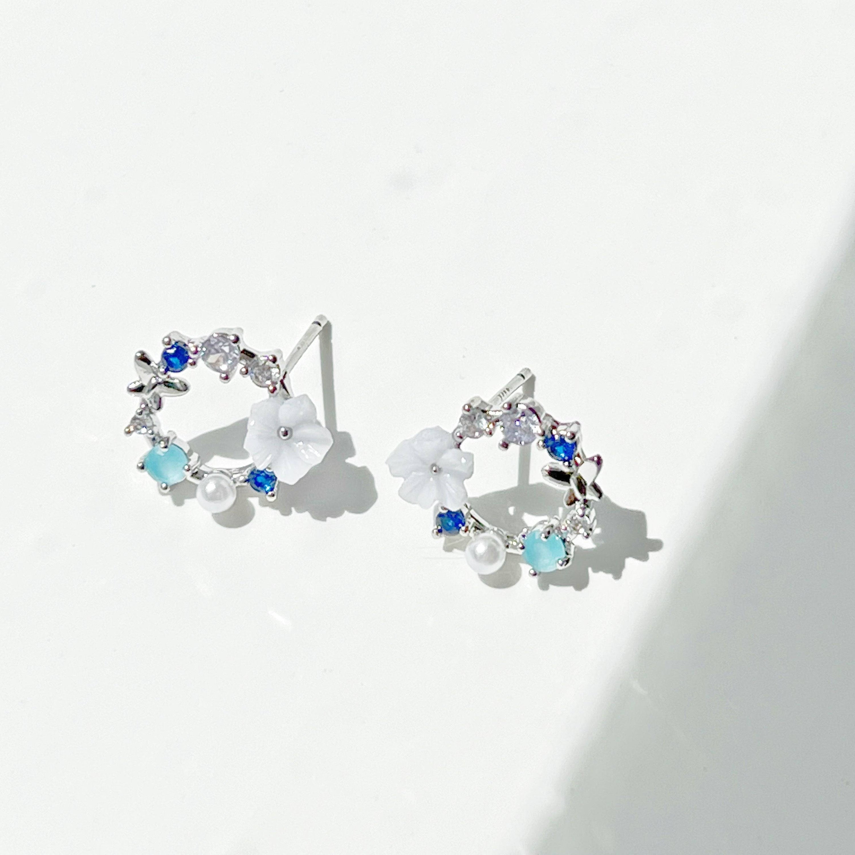 A pair of elegant blue flower wreath earrings featuring blue zircon and pearl, set in gold-plated bronze with sterling silver ear studs.