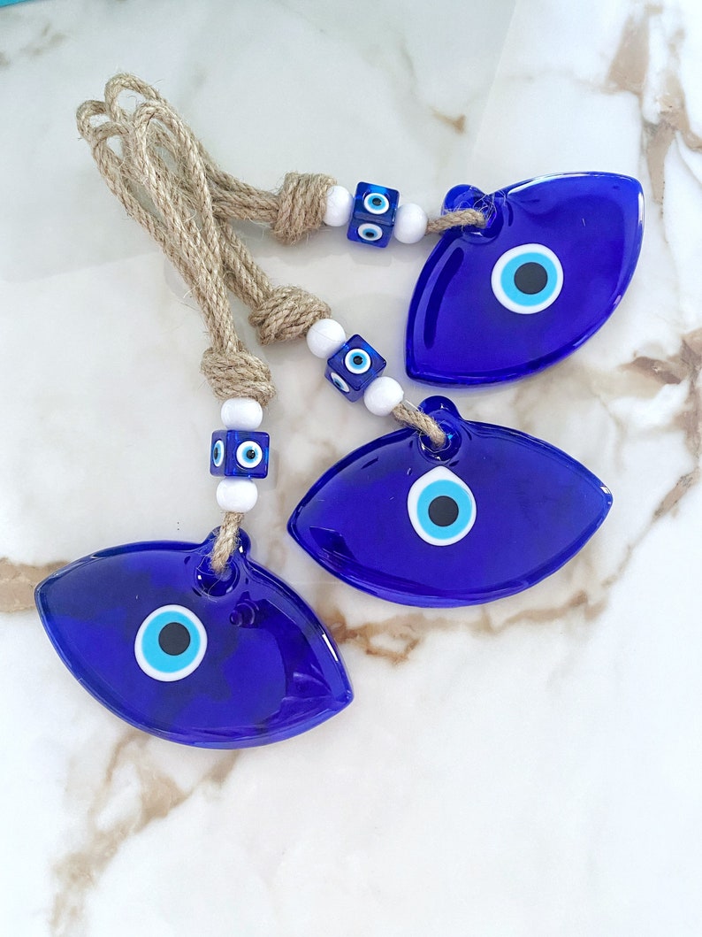 Handmade Blue Greek Evil Eye Wall Hanging featuring a large eye design and macrame details, perfect for home decor.