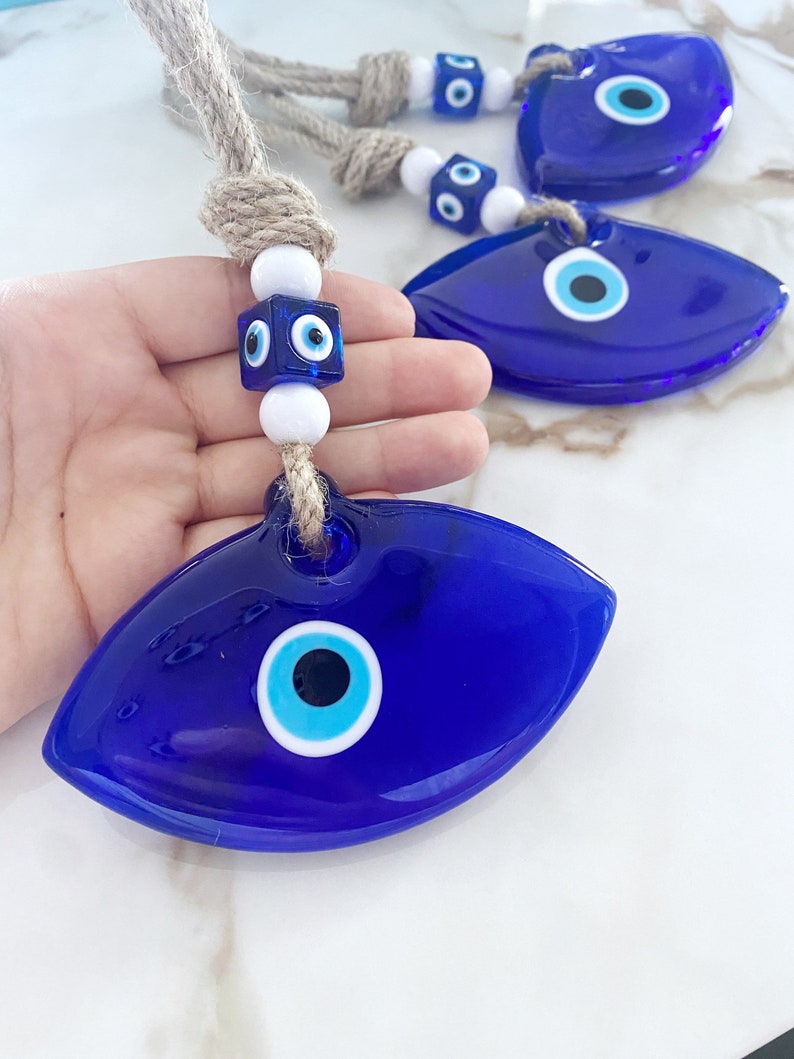 Handmade Blue Greek Evil Eye Wall Hanging featuring a large eye design and macrame details, perfect for home decor.