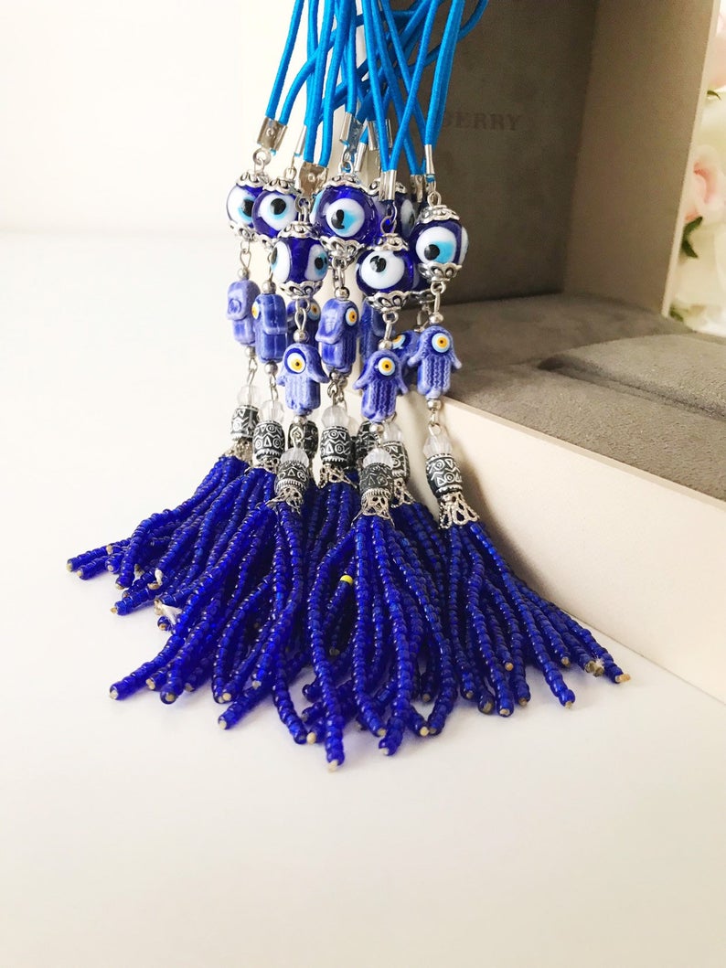 Handmade blue hamsa hand evil eye charm for car mirror, featuring glass beads and a protective symbol.