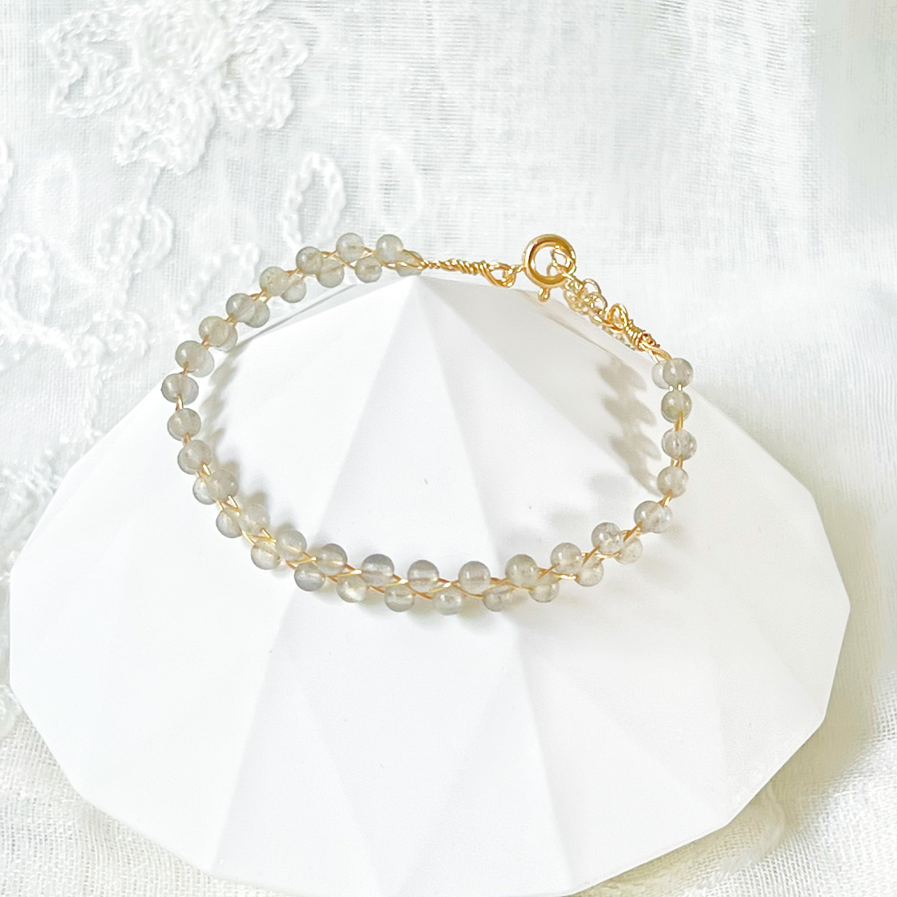 A beautiful Blue Moonstone Stacking Bracelet featuring natural moonstone beads woven with gold-plated wires, showcasing a unique waving design.