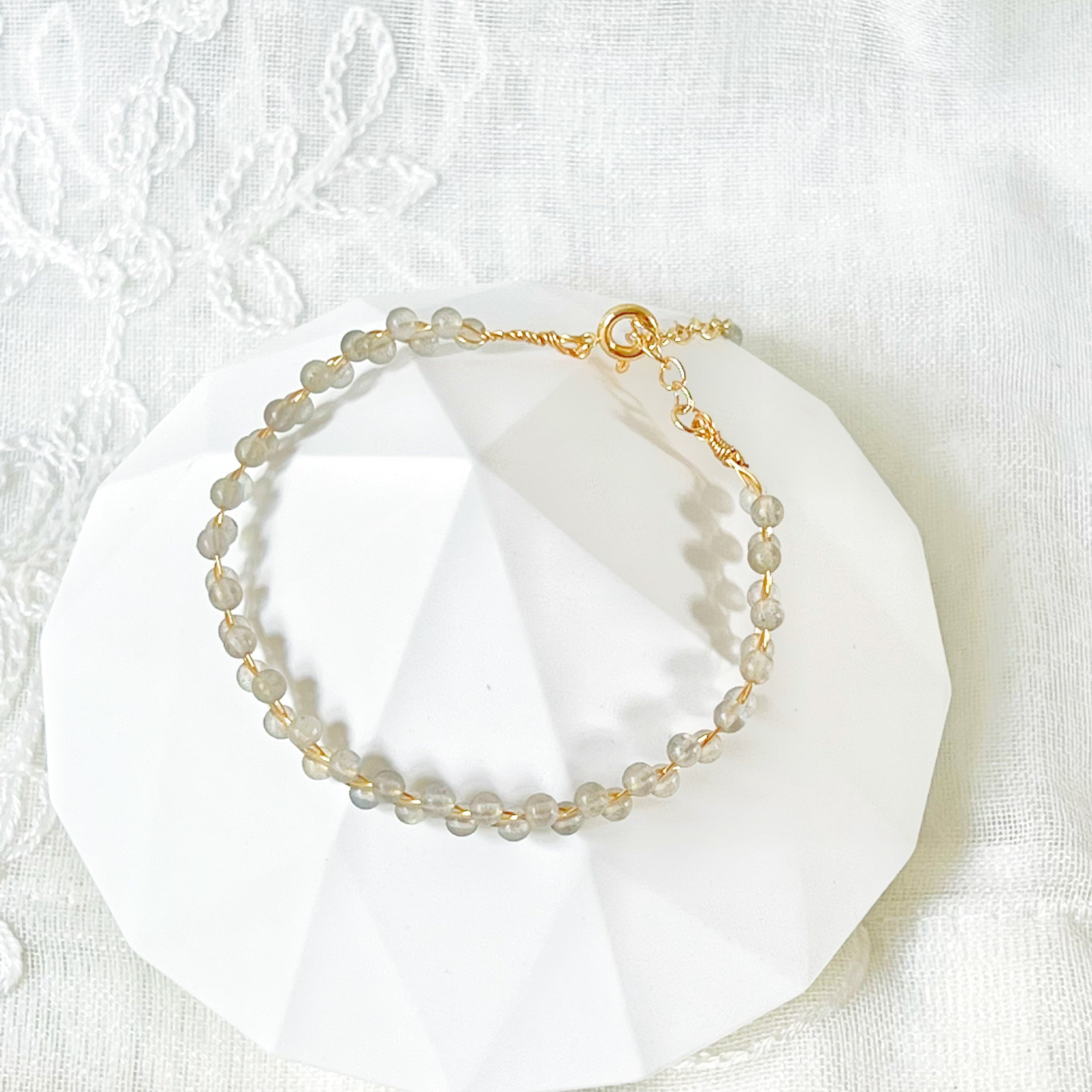 A beautiful Blue Moonstone Stacking Bracelet featuring natural moonstone beads woven with gold-plated wires, showcasing a unique waving design.