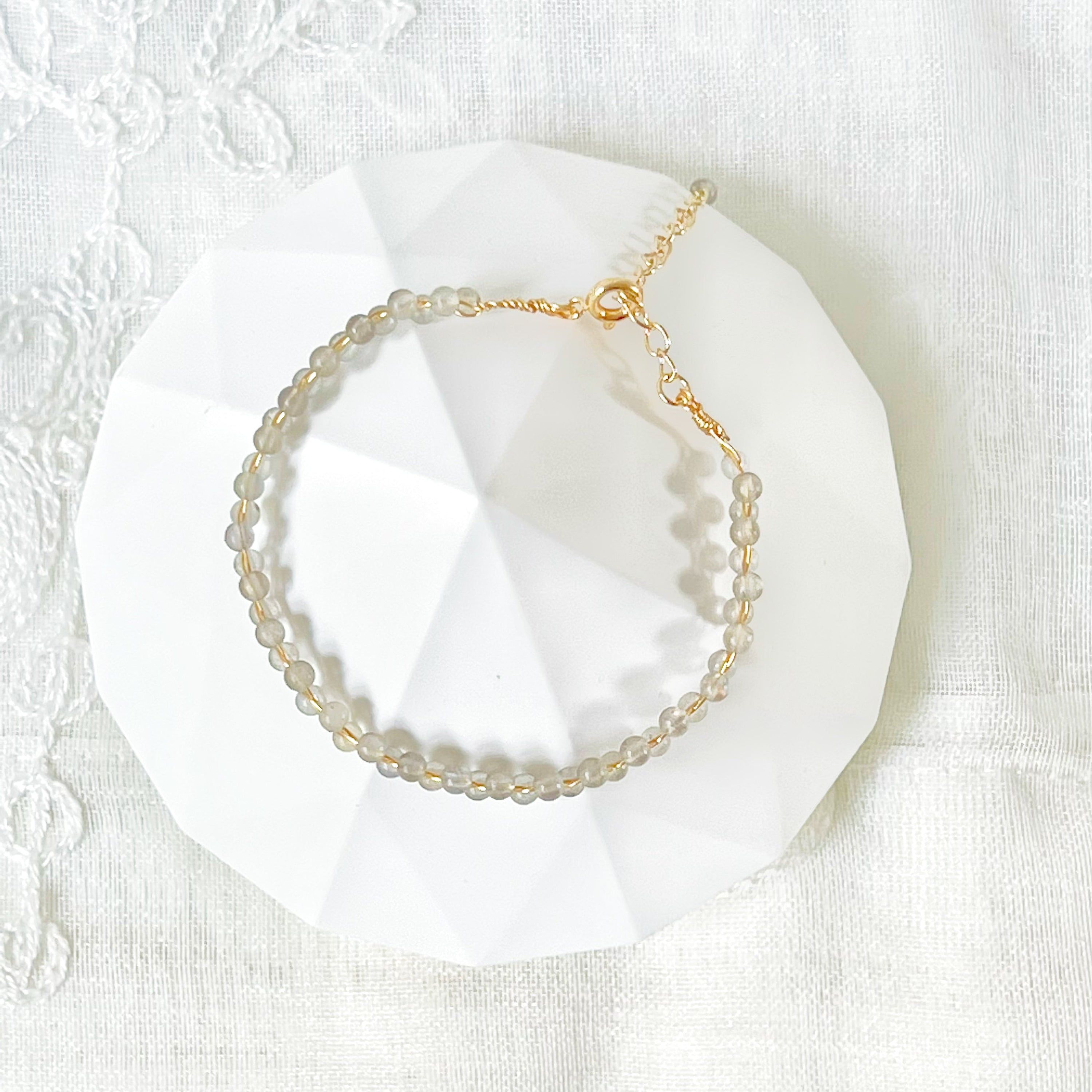 A beautiful Blue Moonstone Stacking Bracelet featuring natural moonstone beads woven with gold-plated wires, showcasing a unique waving design.