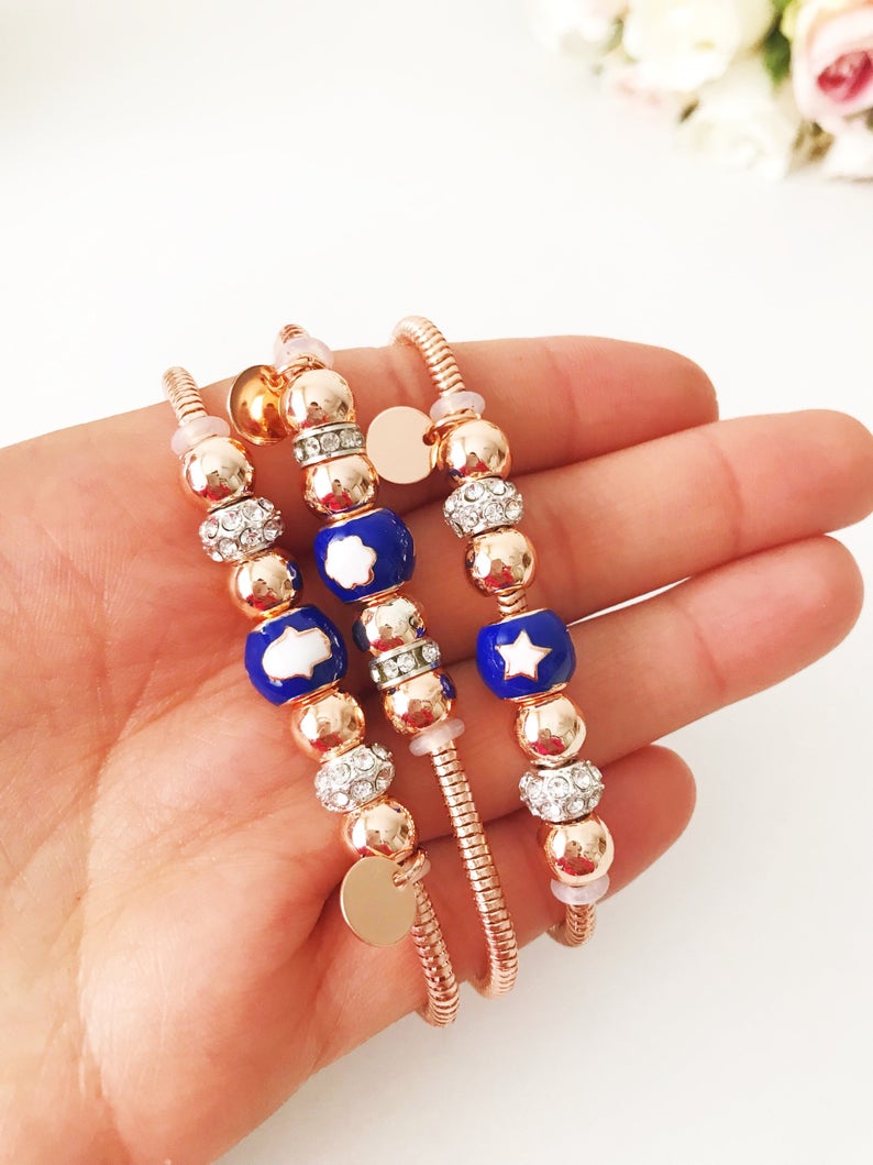 Blue Pandora Charm Bracelet featuring a rose gold chain and various charms including hamsa, four-leaf clover, and star figures.