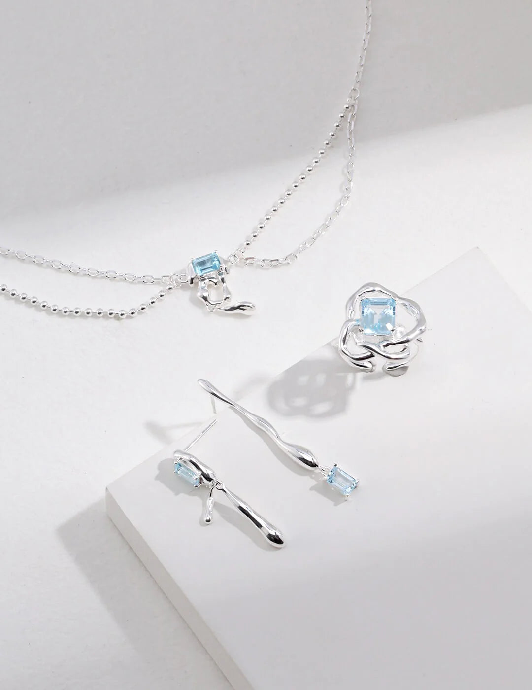 Handmade blue topaz drop earrings in sterling silver, showcasing unique gemstone qualities and artistic design.