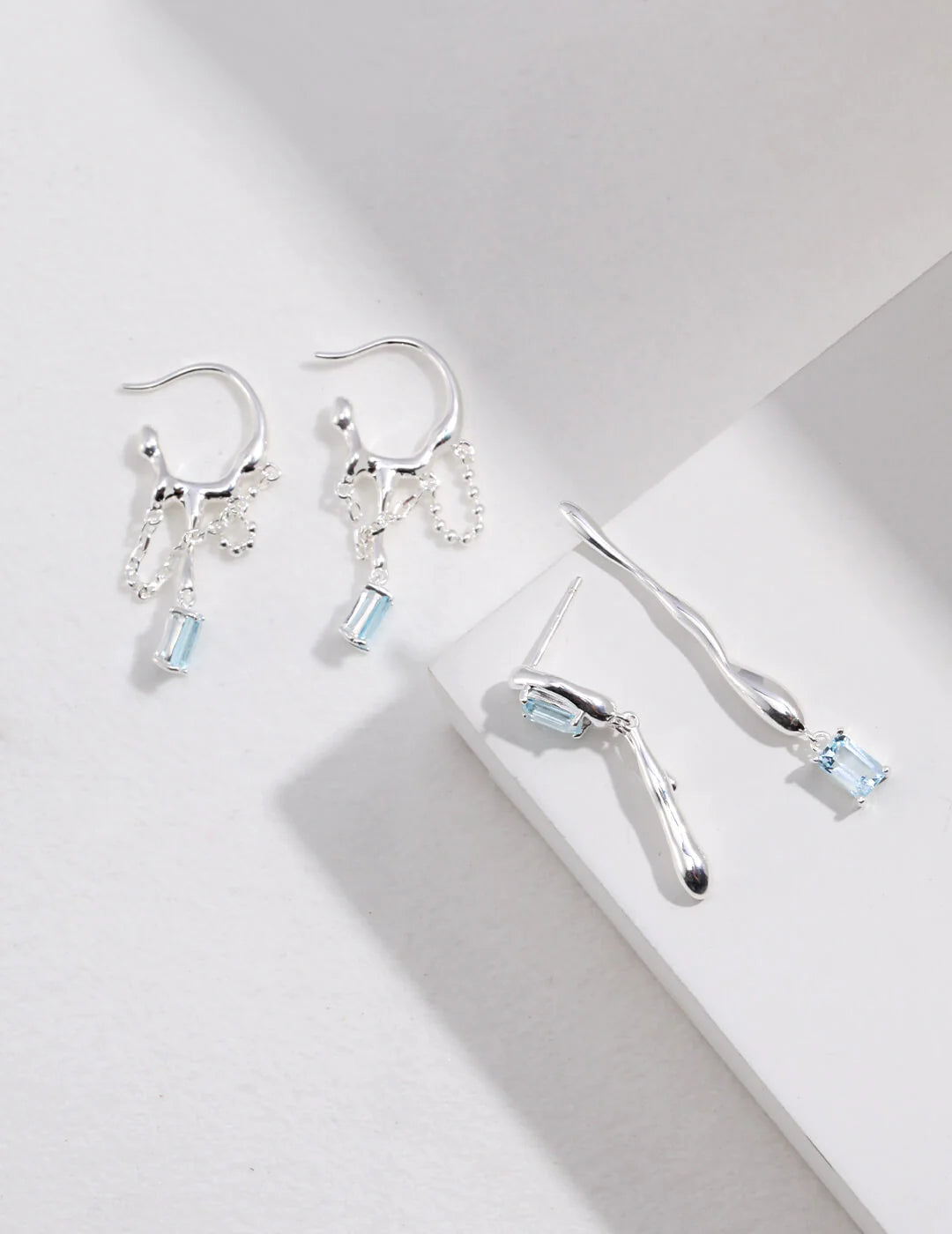 Handmade blue topaz drop earrings in sterling silver, showcasing unique gemstone qualities and artistic design.