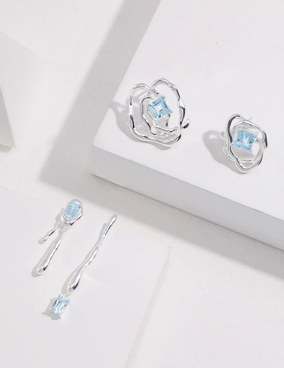 Handmade blue topaz drop earrings in sterling silver, showcasing unique gemstone qualities and artistic design.