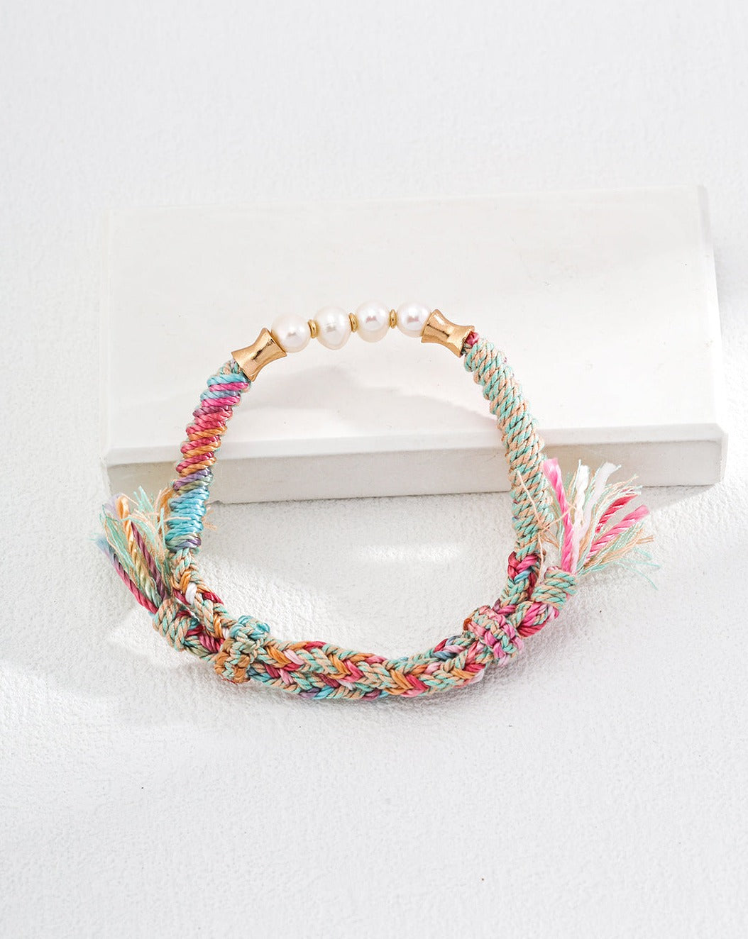 A handmade natural pearl bracelet featuring colorful hemp rope, showcasing a bohemian style with adjustable length for a perfect fit.