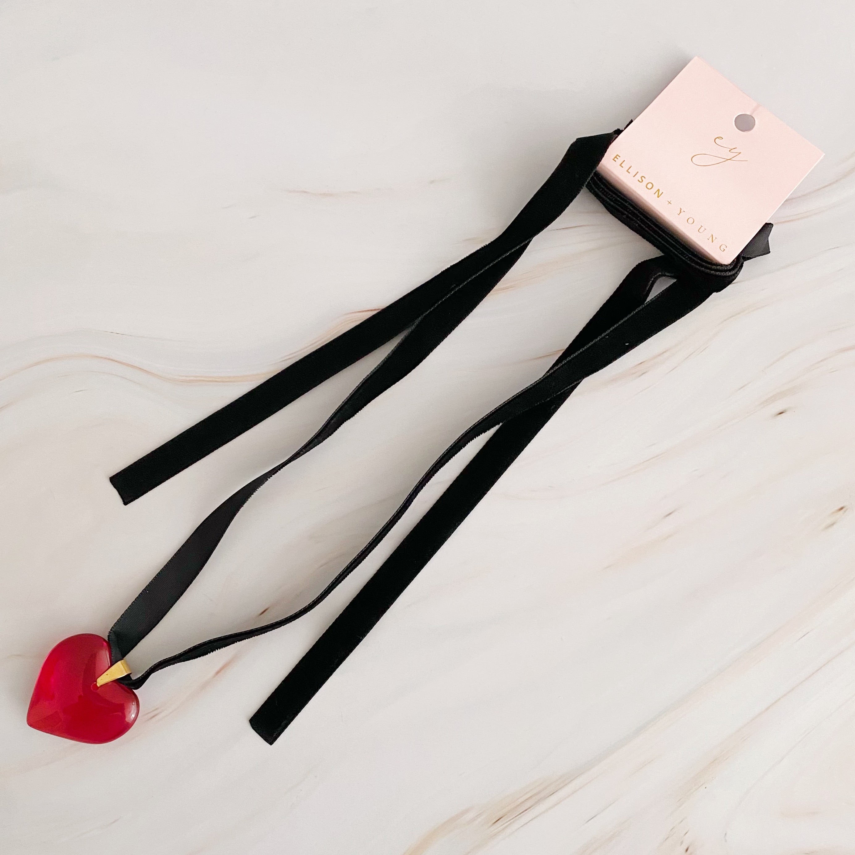 Bold In Red Black Sash Necklace featuring a red heart pendant and a black velvet sash, elegantly displayed on a neutral background.