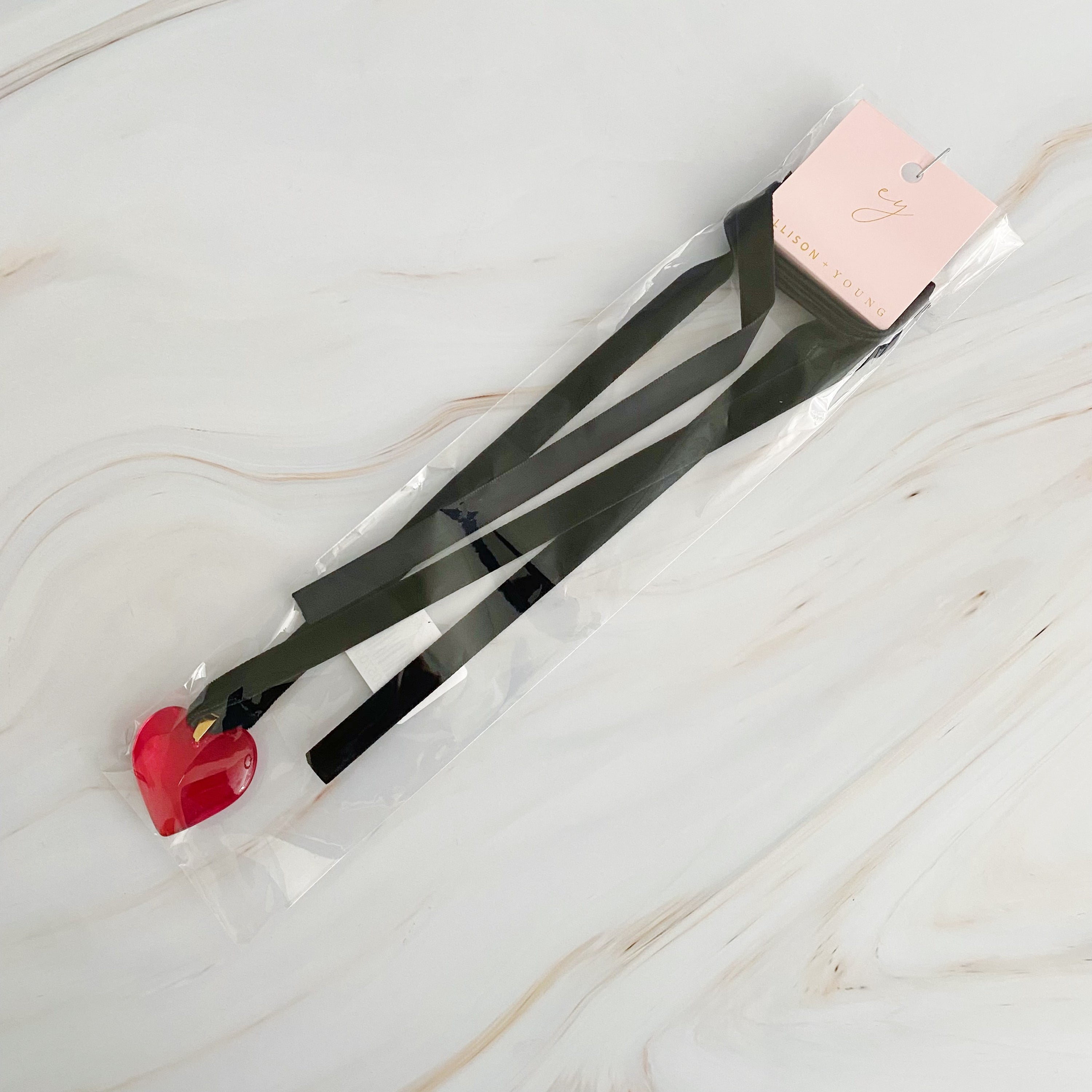 Bold In Red Black Sash Necklace featuring a red heart pendant and a black velvet sash, elegantly displayed on a neutral background.