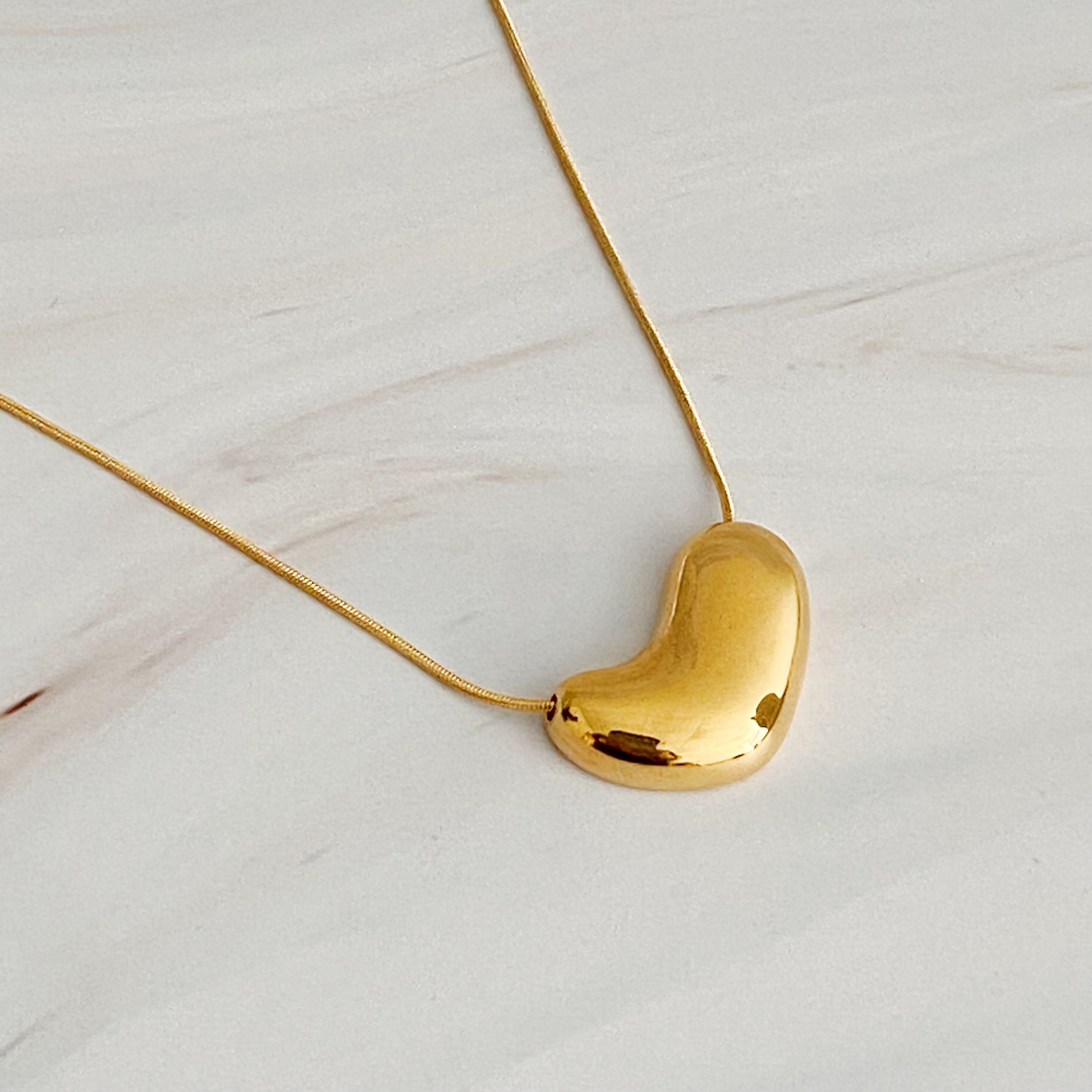 Bold Molten Heart Necklace featuring a rounded heart pendant on a herringbone chain, elegantly designed in 18k gold plating.