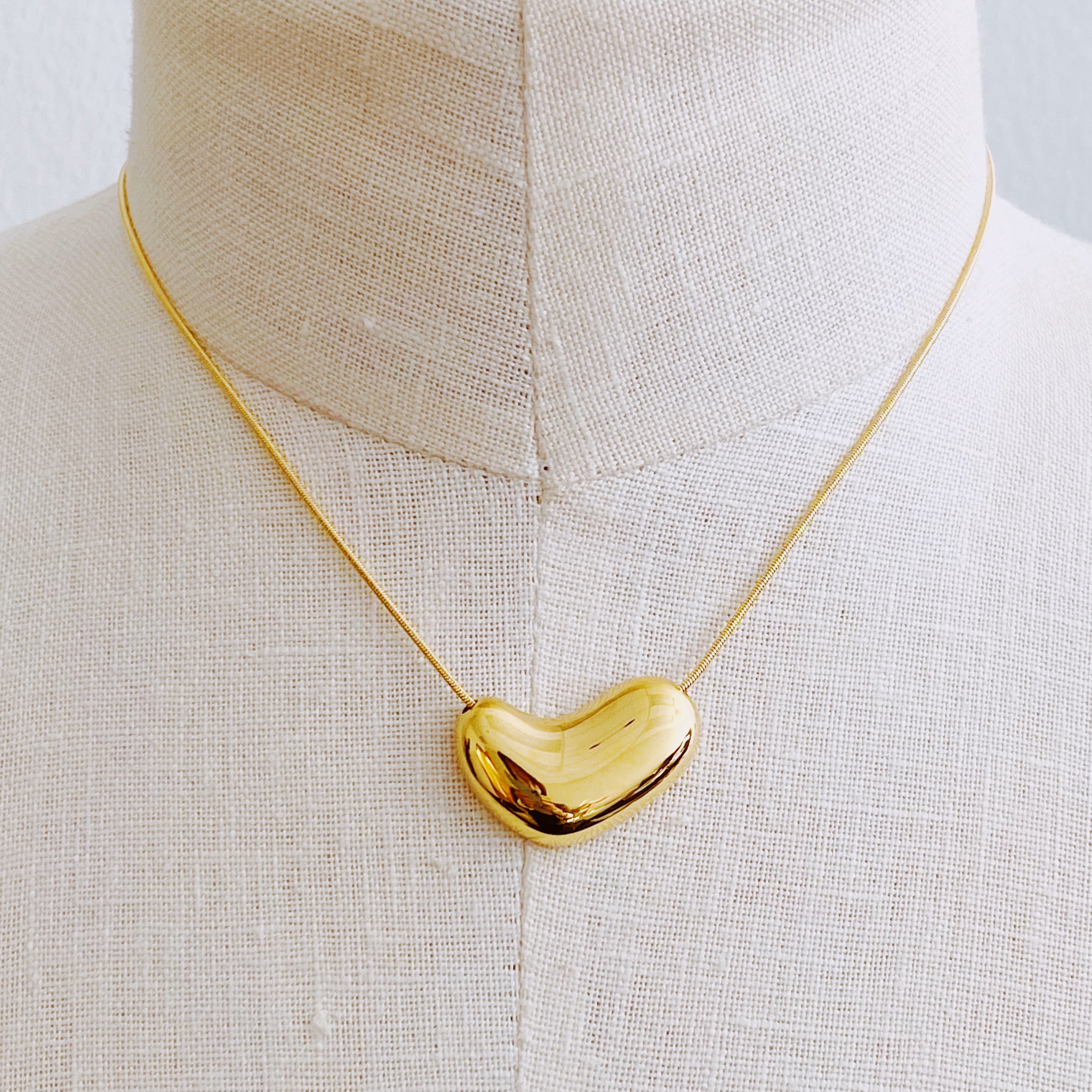 Bold Molten Heart Necklace featuring a rounded heart pendant on a herringbone chain, elegantly designed in 18k gold plating.