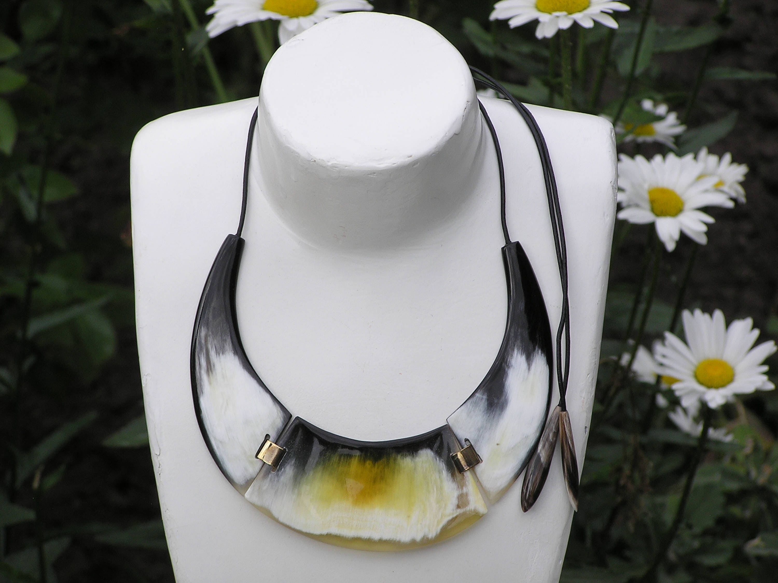 A unique black horn necklace in a half-moon shape, showcasing intricate patterns and a glossy finish, perfect for any outfit.