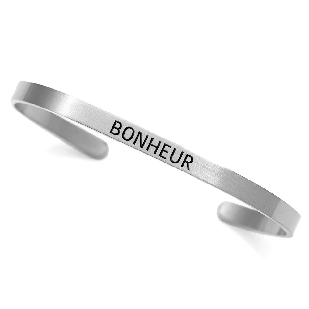 A dainty stainless steel cuff bracelet with the word 'Bonheur' engraved, symbolizing happiness and French inspiration.