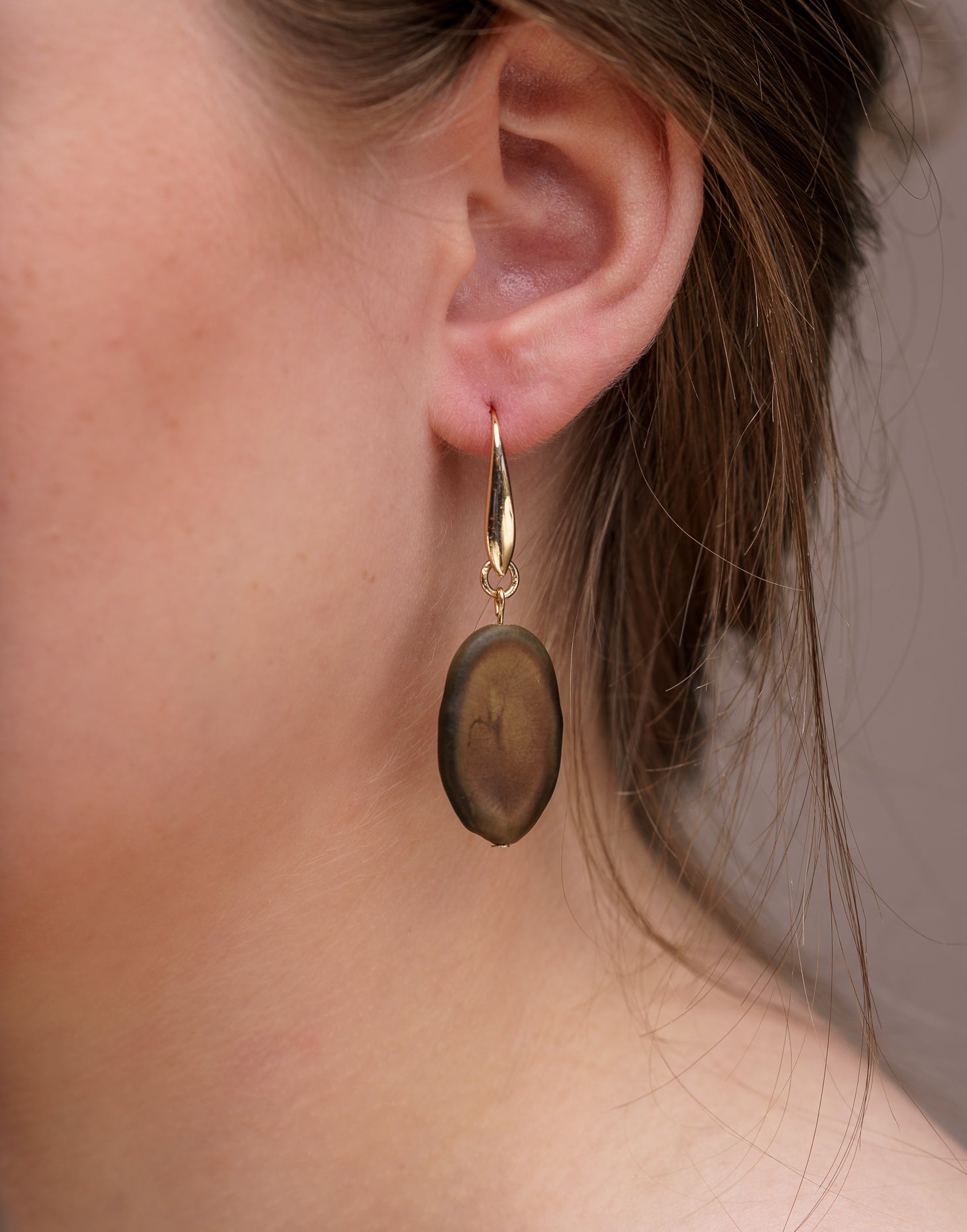 A pair of elegant Botanic Earrings made from Guapuruvu seeds with raw brass hoops, showcasing unique natural variations.