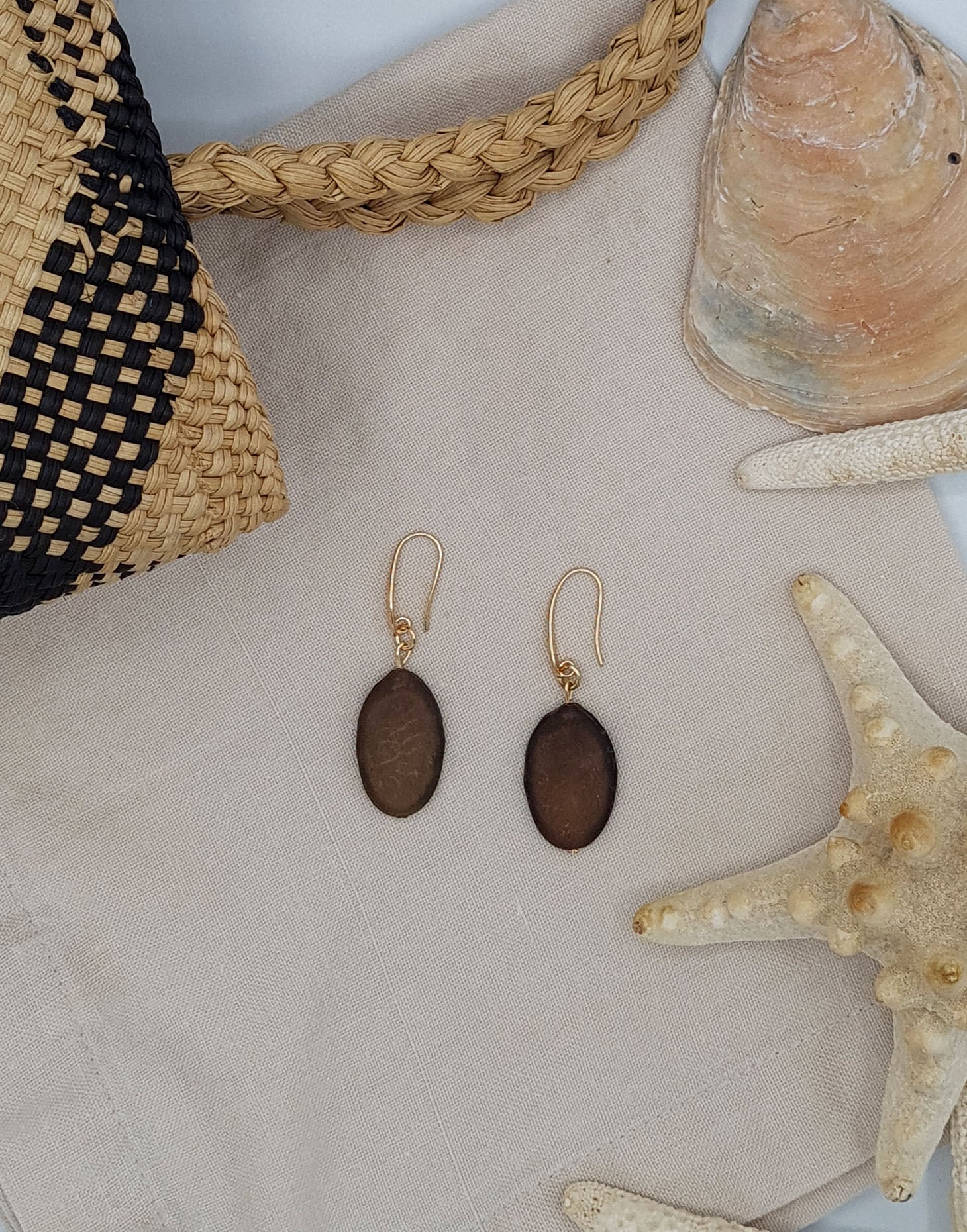 A pair of elegant Botanic Earrings made from Guapuruvu seeds with raw brass hoops, showcasing unique natural variations.