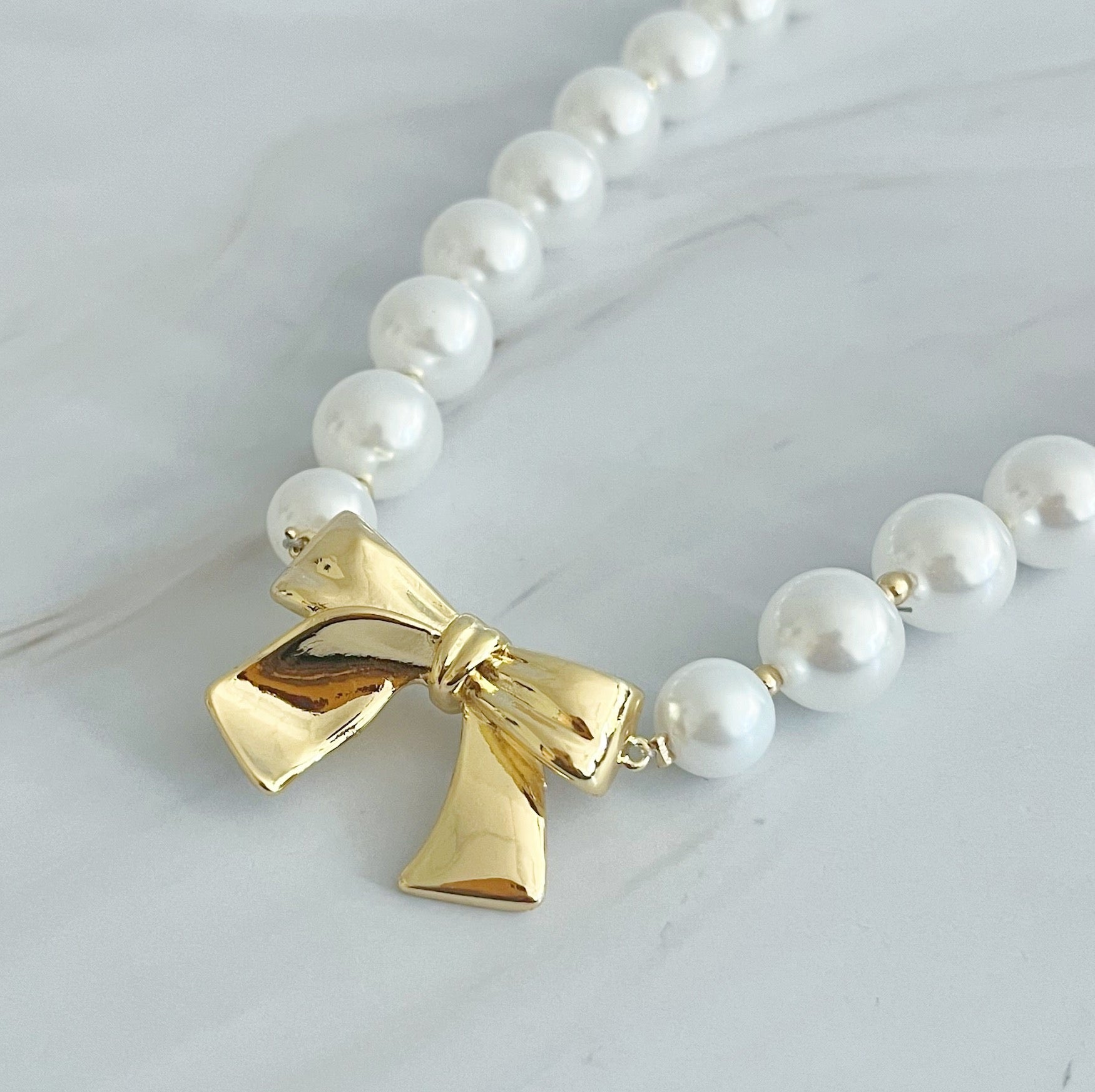 Elegant Bow And Pearls Necklace featuring glass pearls and a gold plated bow centerpiece.