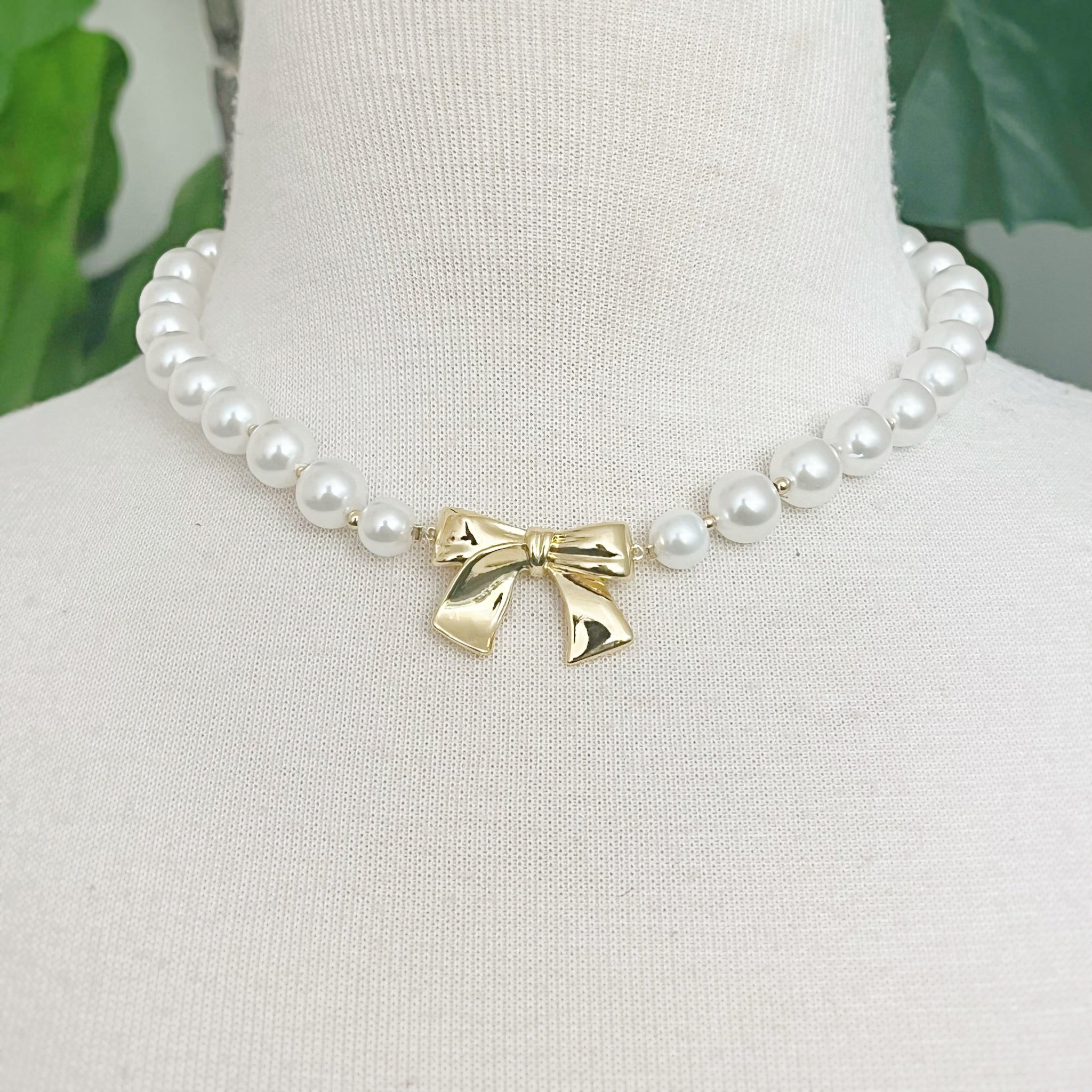 Elegant Bow And Pearls Necklace featuring glass pearls and a gold plated bow centerpiece.