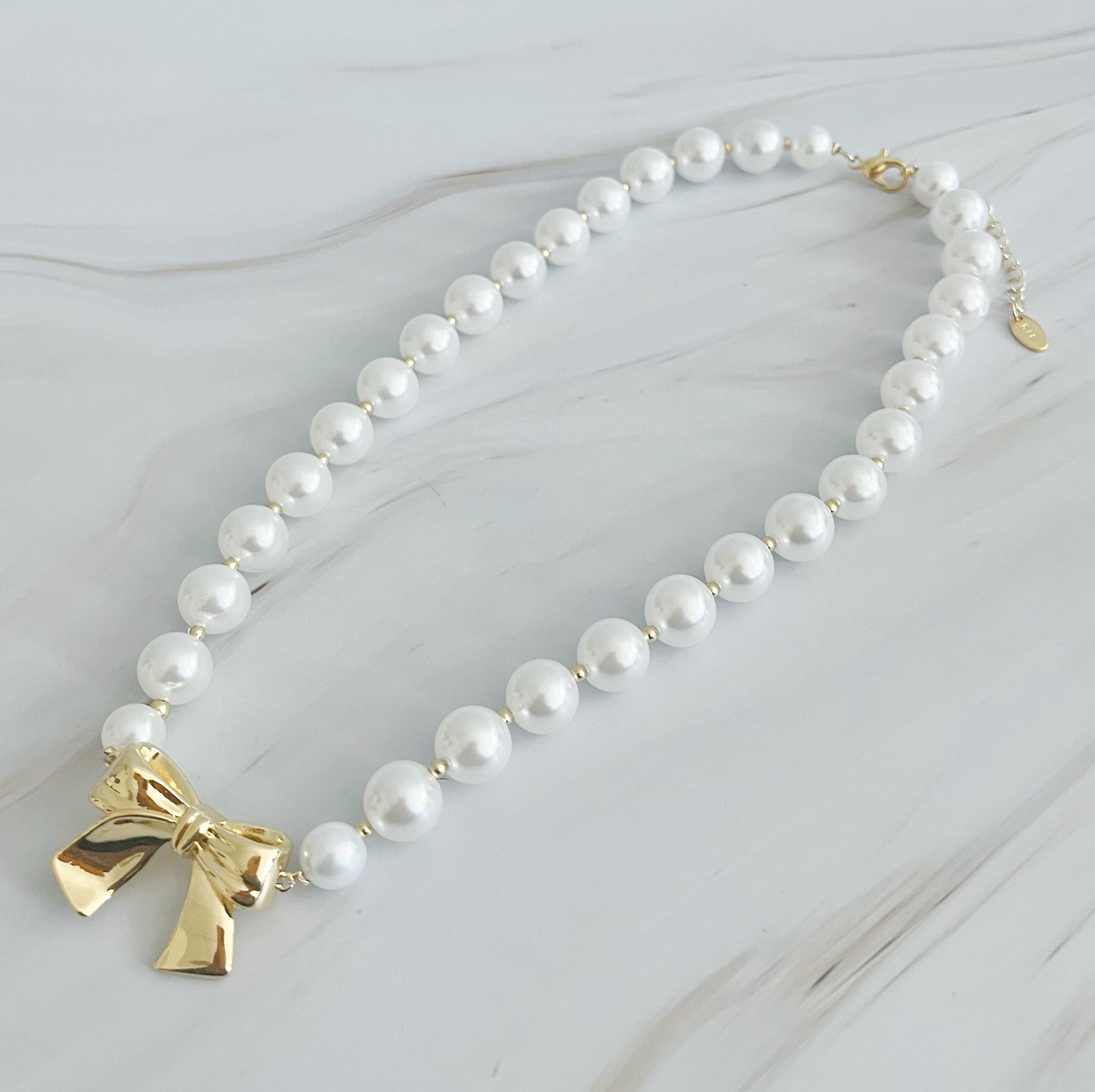 Elegant Bow And Pearls Necklace featuring glass pearls and a gold plated bow centerpiece.