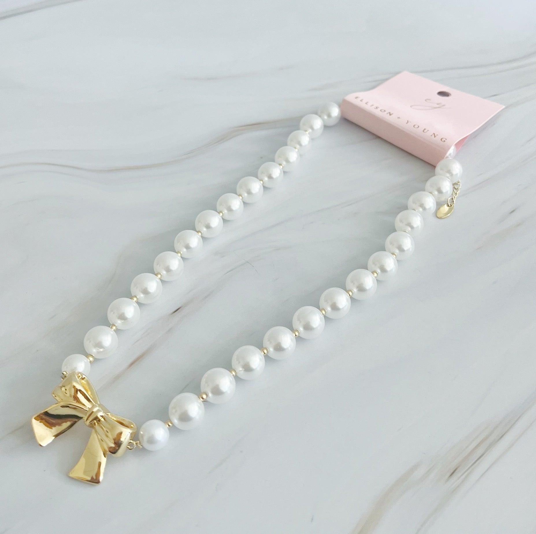 Elegant Bow And Pearls Necklace featuring glass pearls and a gold plated bow centerpiece.